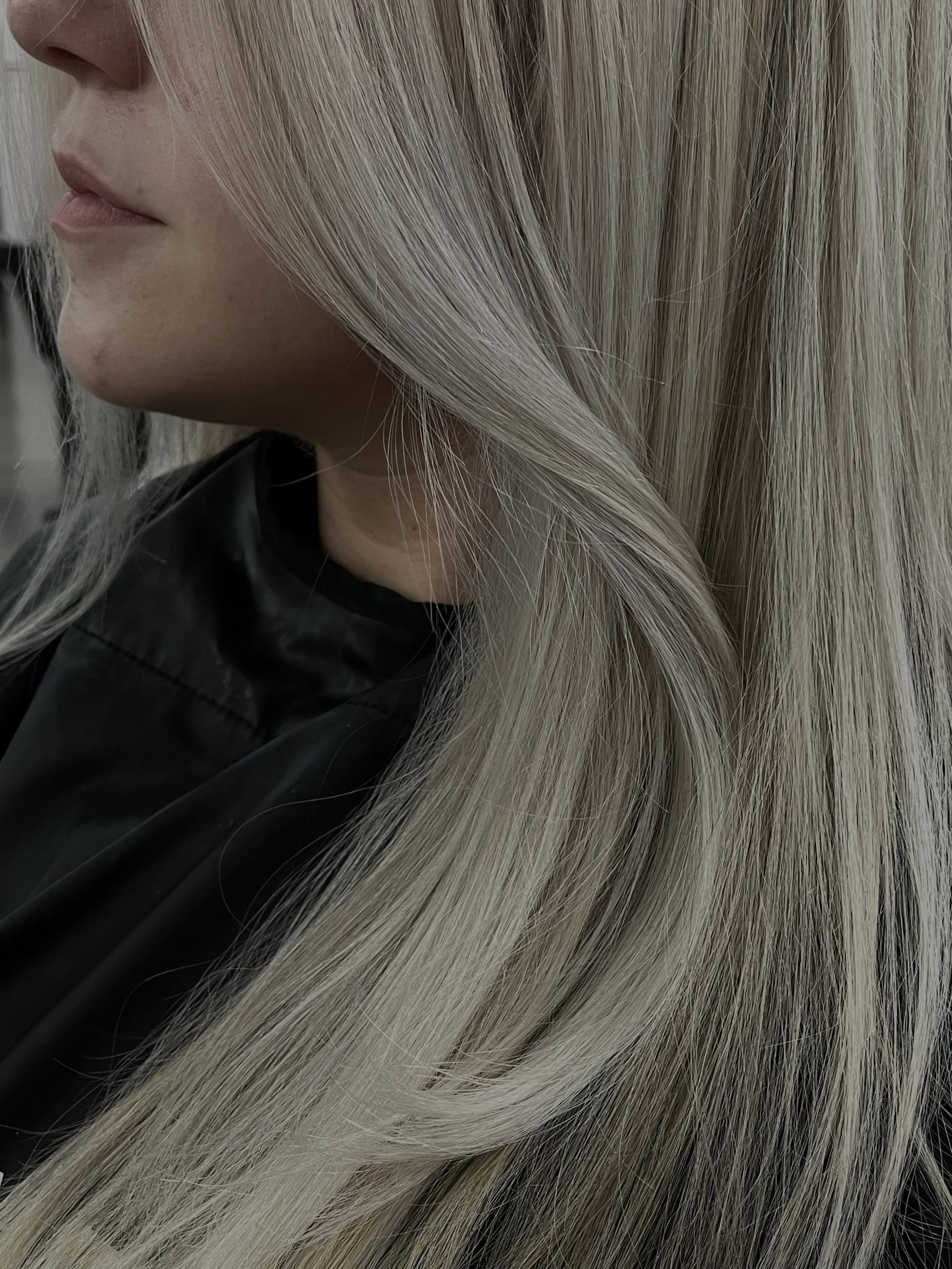 A woman with long, blonde hair and a mustache, wearing a black cape.