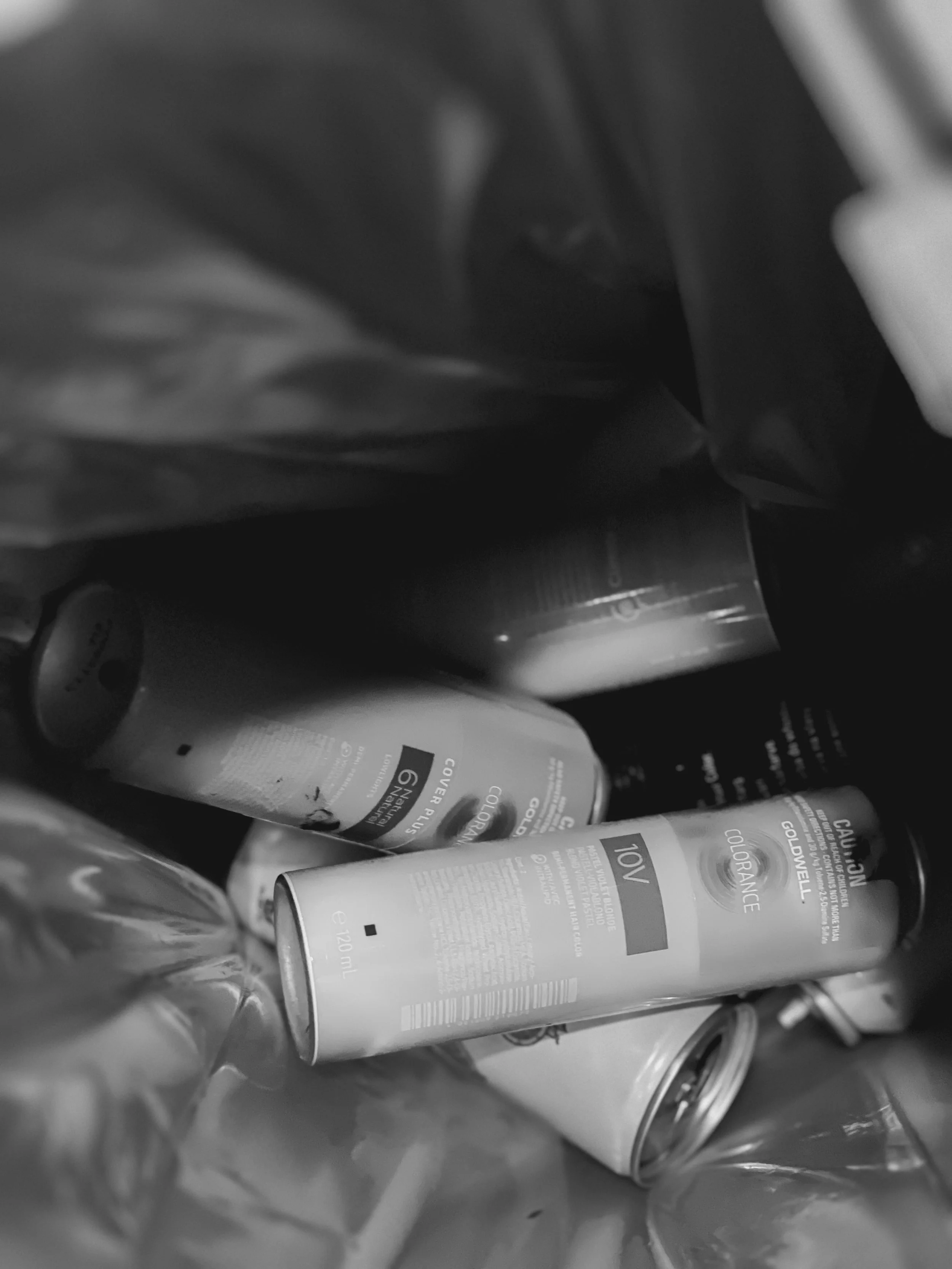 Black and white photo of various cans and bottles inside a bag or container.