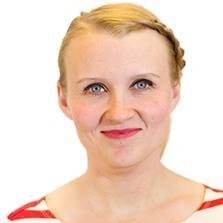 Close-up portrait of a woman with blonde hair, wearing a striped shirt, smiling against a white background.