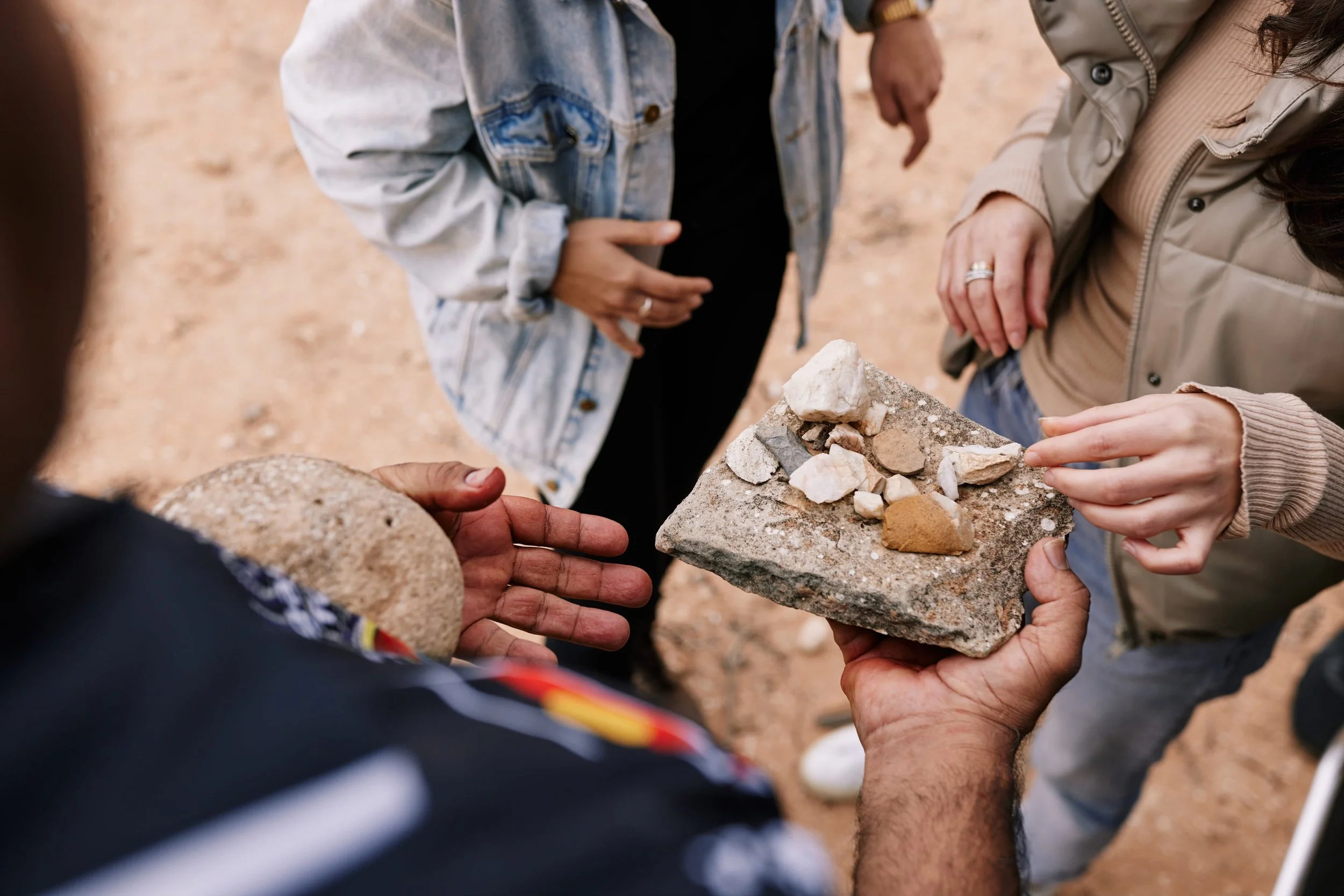 Group of people examining rocks on a stone slab during an outdoor activity.