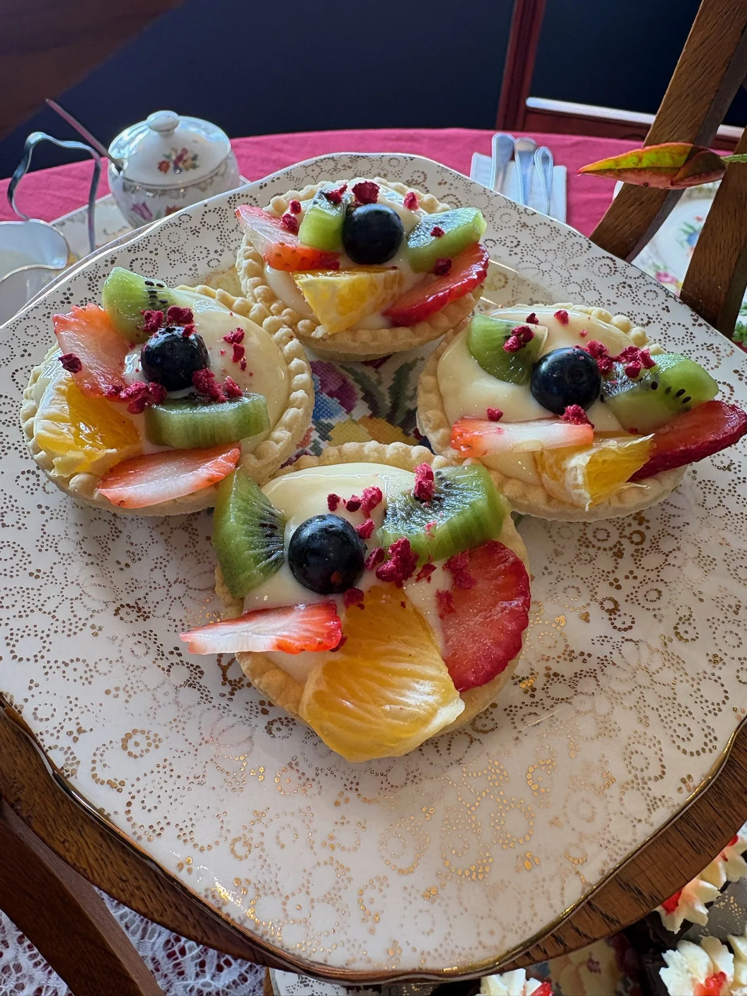 Assorted fruit tarts topped with strawberries, blueberries, kiwi, and other mixed fruits on a decorative plate.