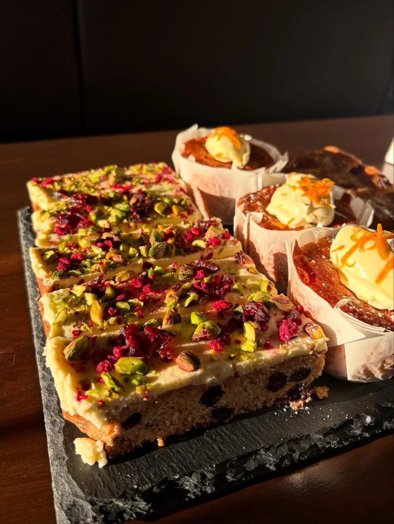 A slate platter with a selection of Bella's cakes and slices.