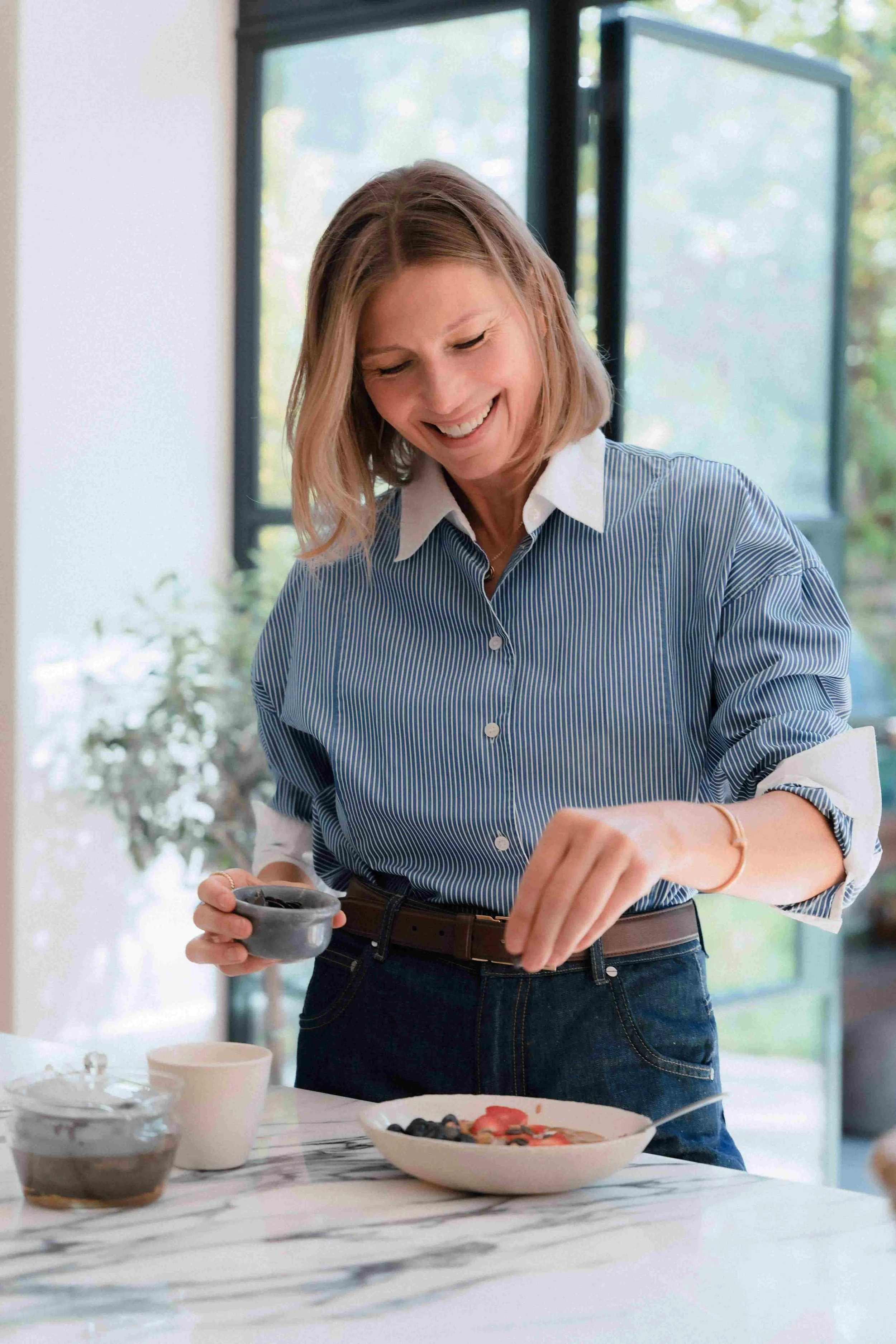 Midlife woman calmly cooking a healthy meal in her kitchen to support gut health and ease menopause and acid reflux symptoms