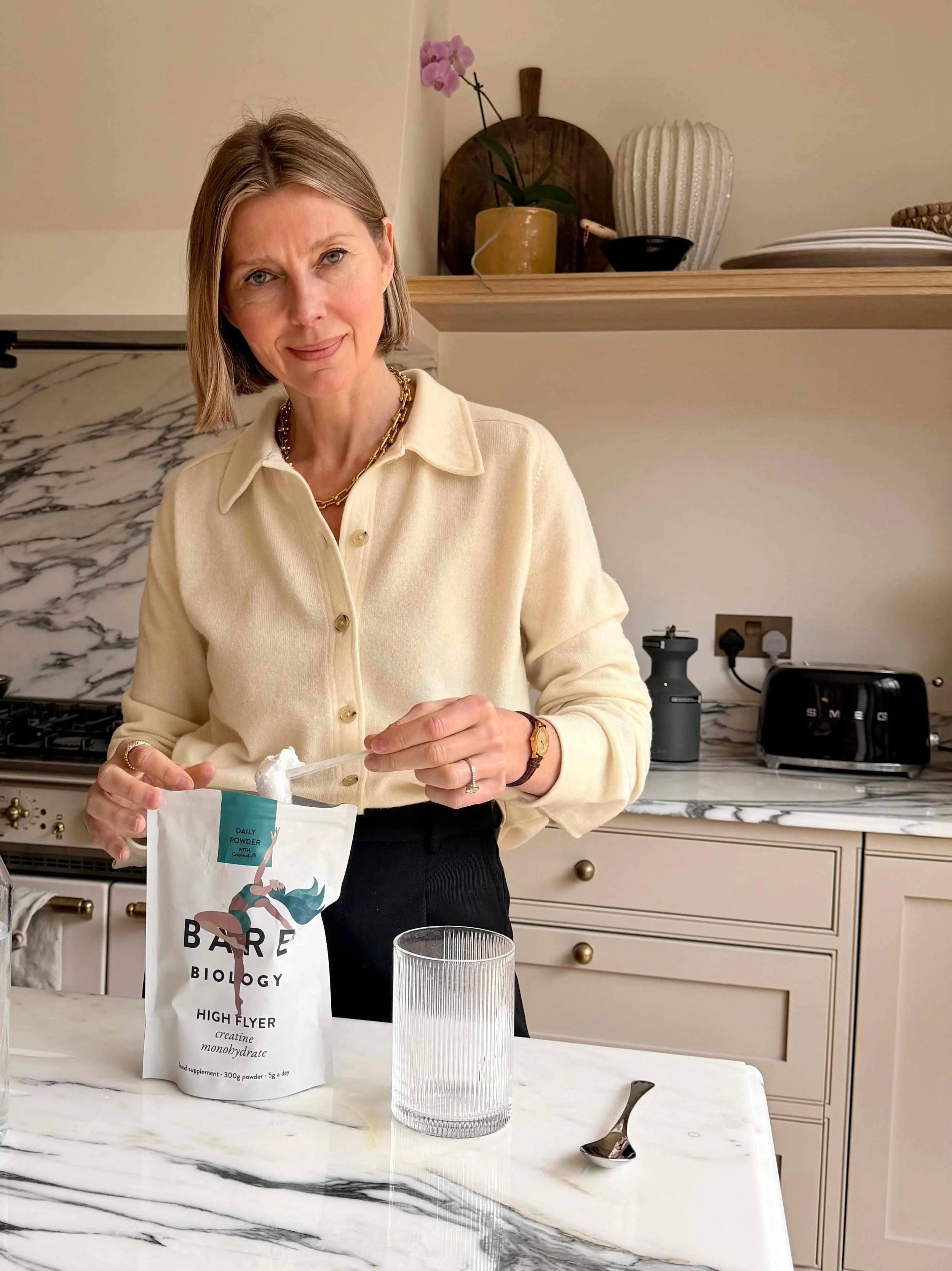 Energetic, healthy woman over 40 holding a creatine supplement bottle, representing creatine for women over 40 and active ageing support.