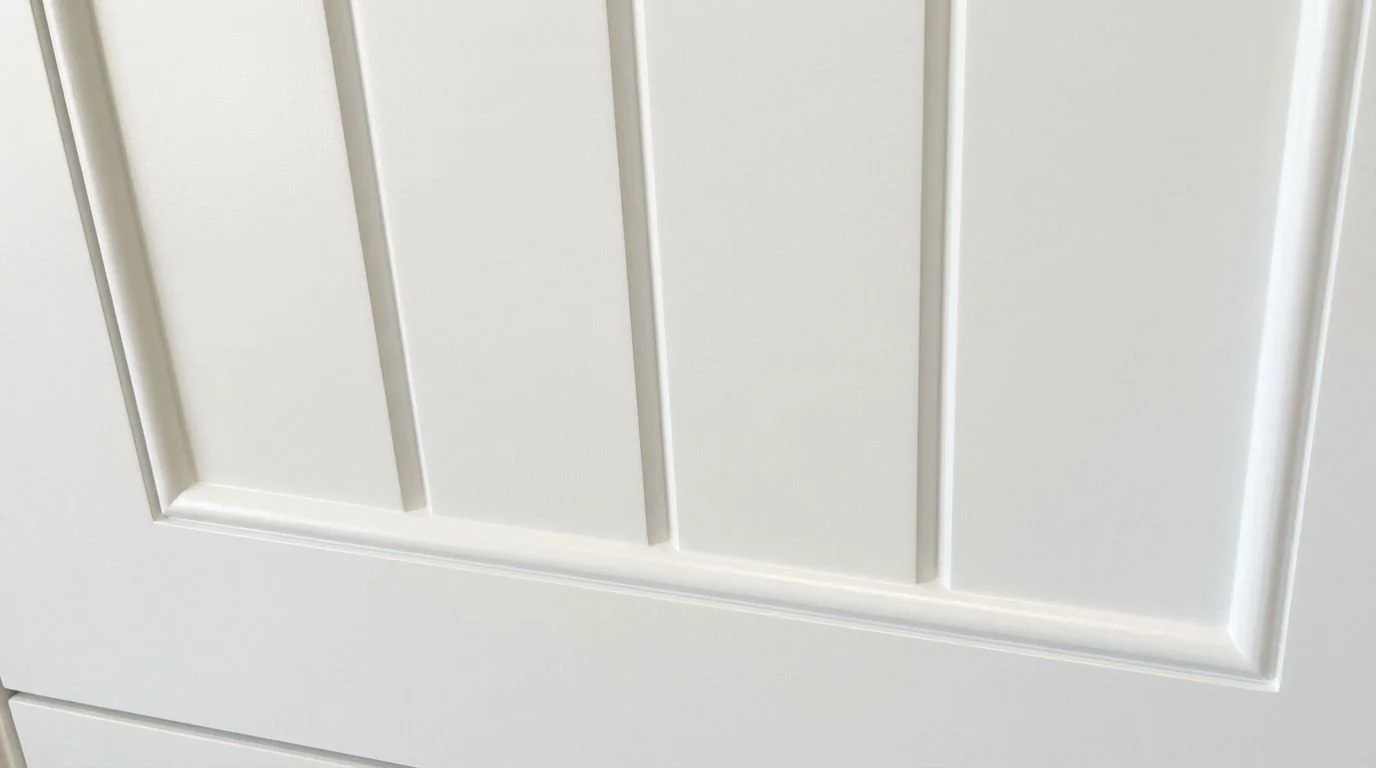 Close-up view of a white wooden door with vertical panels and a raised border at the bottom edge.