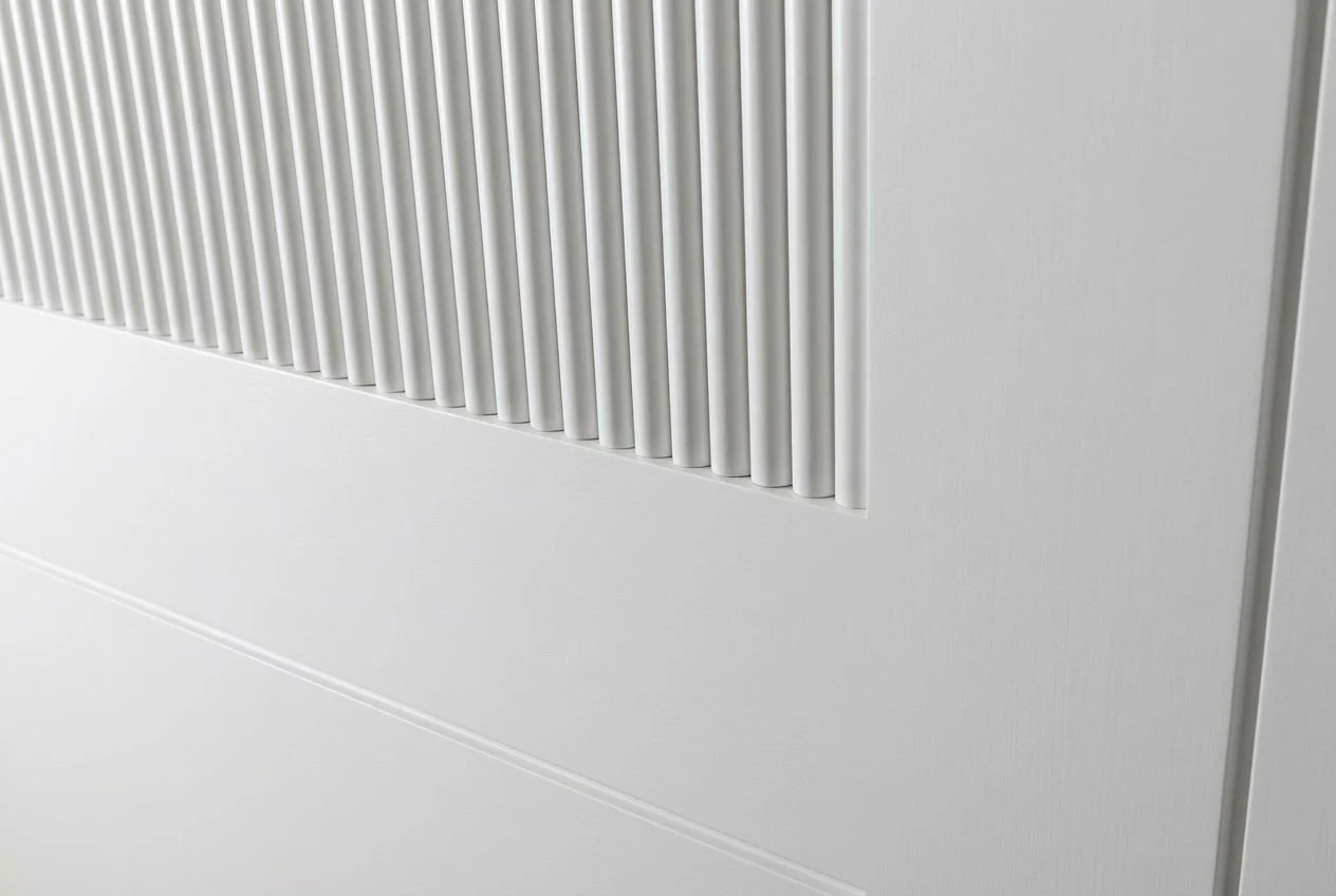 Close-up of a white wall with vertical metallic slats or vents.