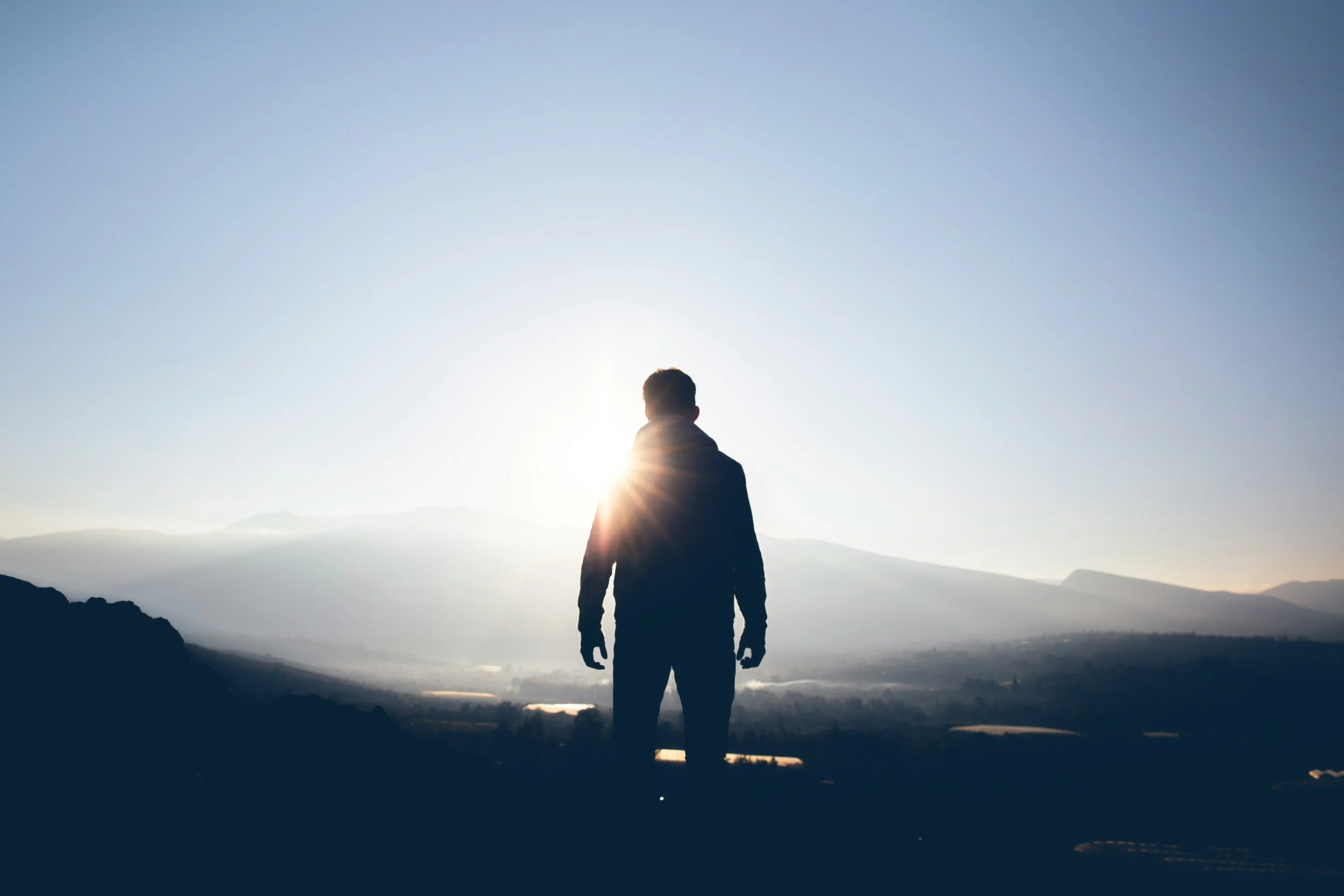 eine Silhouette eines Mannes, der sich den Sonnenaufgang anschaut