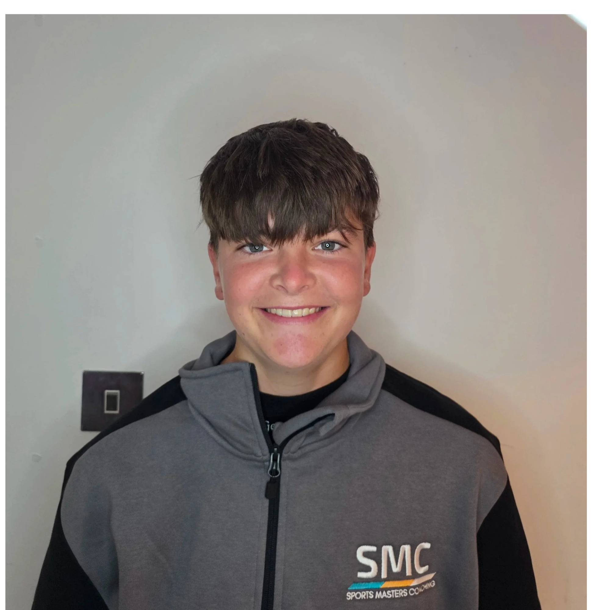 A woman and a girl holding balloon animals inside a room with a wooden floor and white walls, with children in the background.