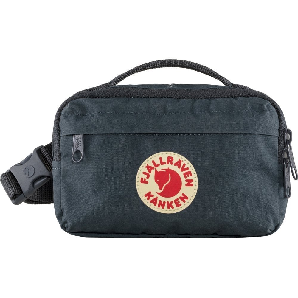 A black Fjällräven Kånken shoulder bag with a circular logo featuring a red fox head and the brand name in red letters on a cream background.