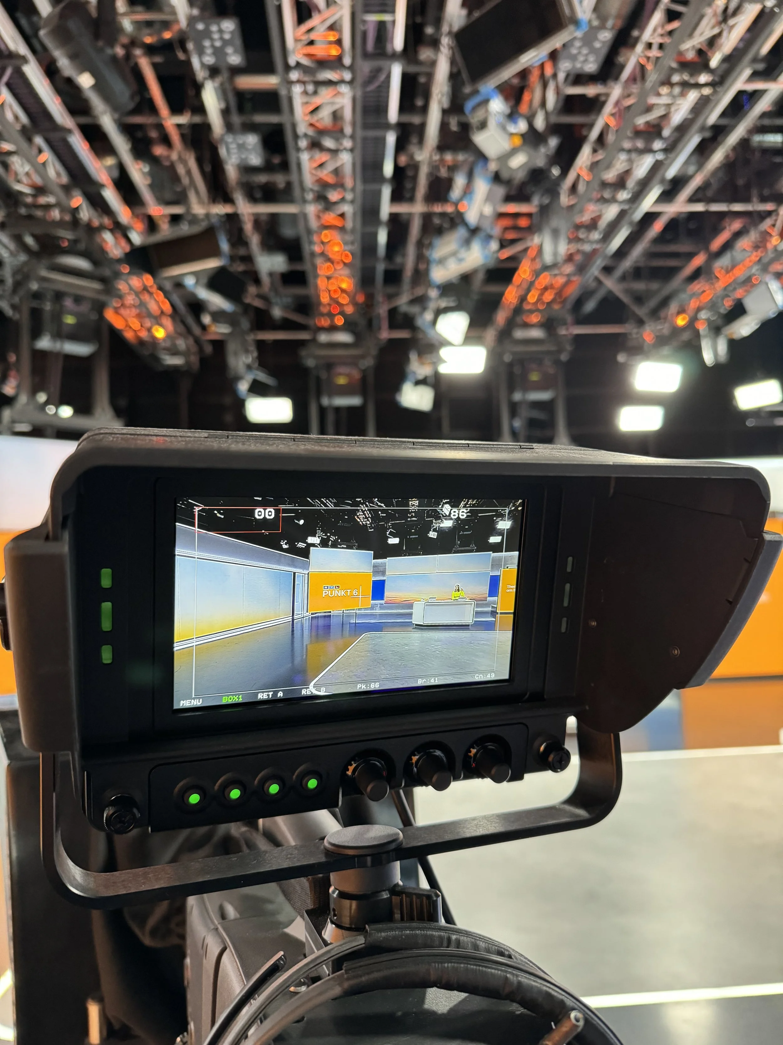 Aufnahme eines Kamera- oder Kameramonitors auf einer Theater- oder TV-Produktion. Im Hintergrund sind Bühnenteile und technische Ausrüstung sichtbar.
