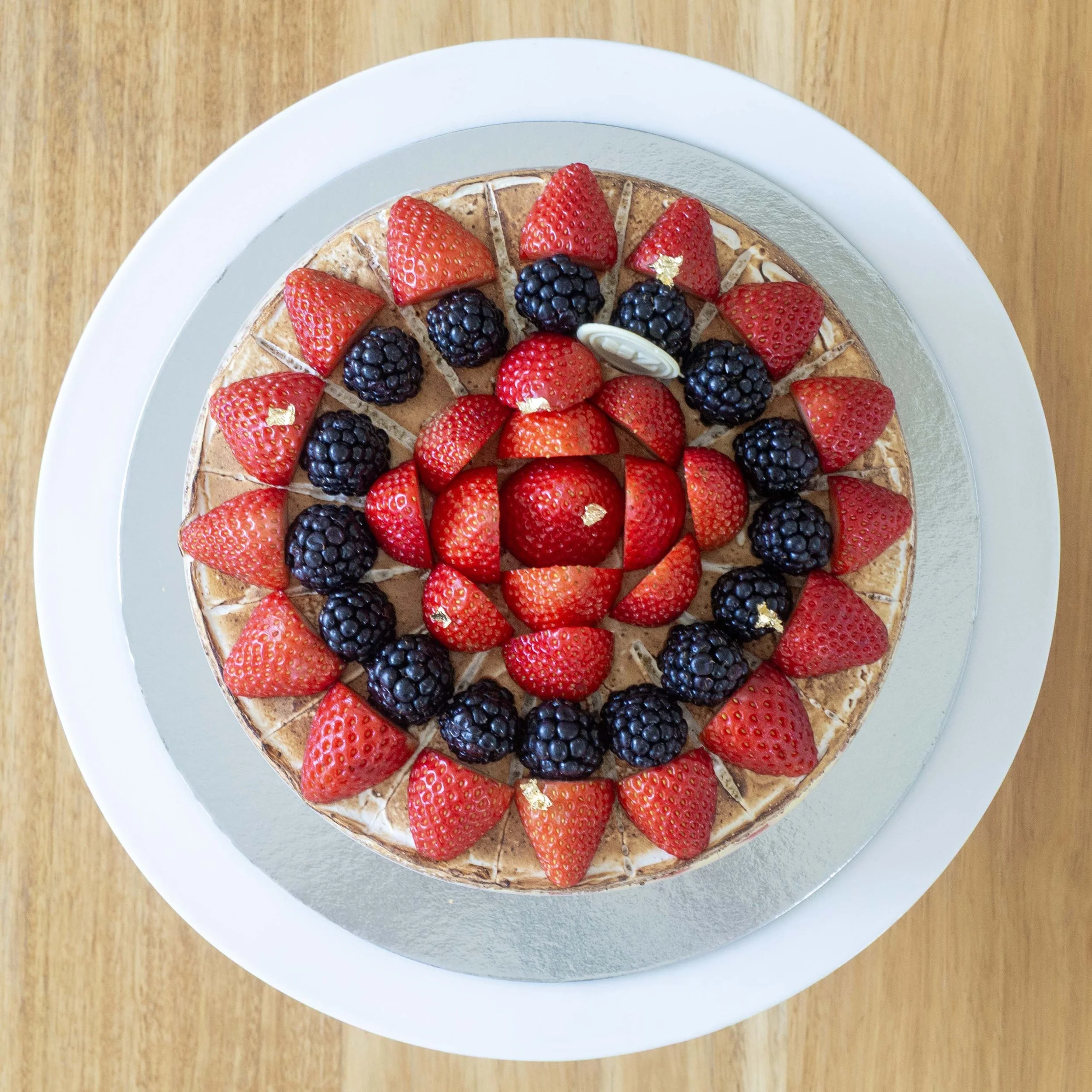a french strawberry cake or fraisier covered with fresh berries viewed from above