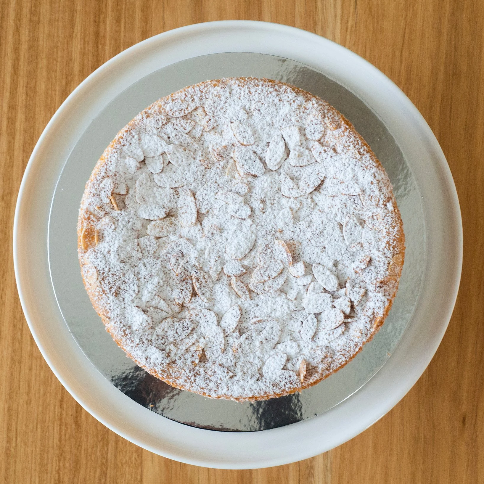 a view from above of a sponge cake filled with lemon curd and cream and topped with toasted almonds