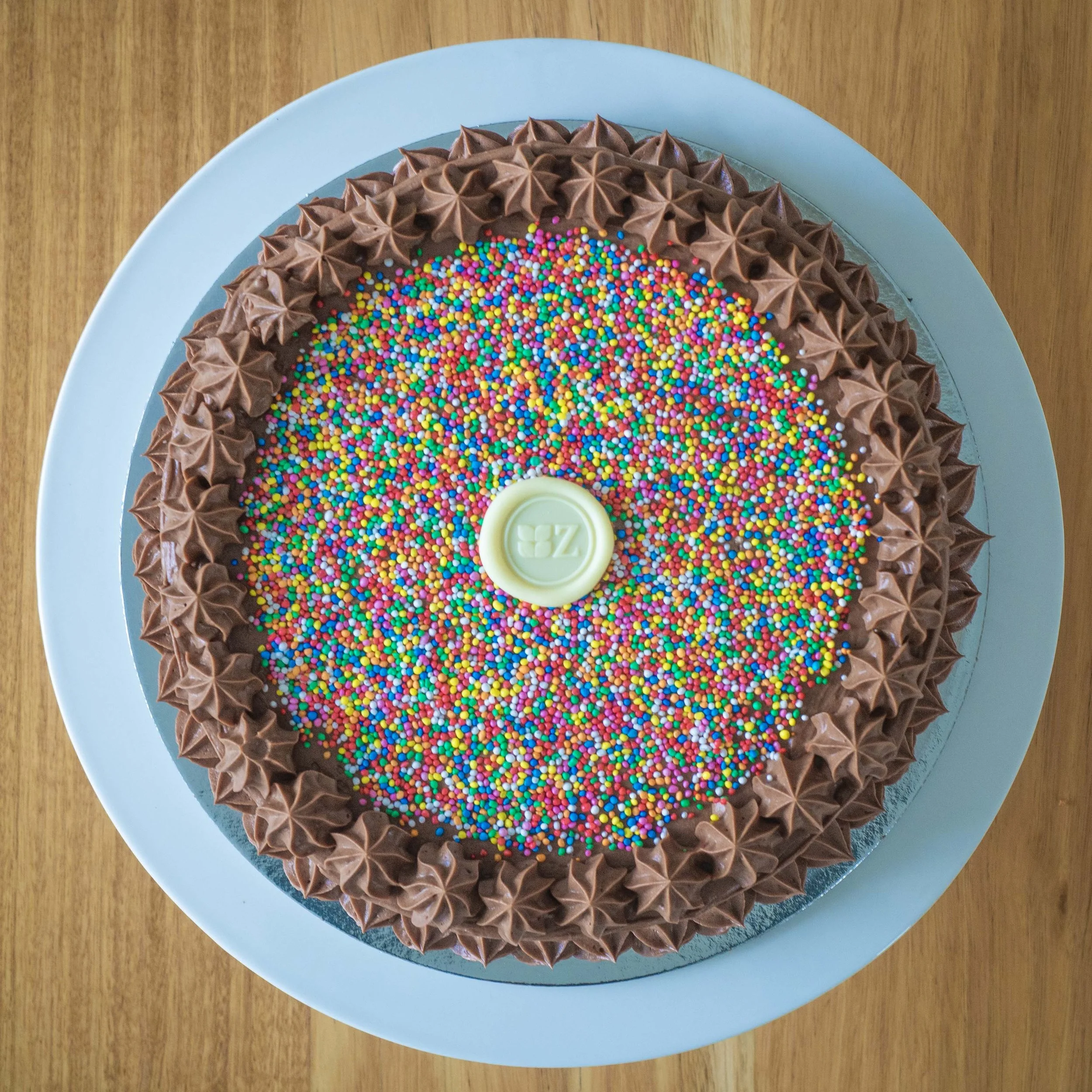 a colourful chocolate birthday cake with 100s and 1000s sprinkles on top viewed from above