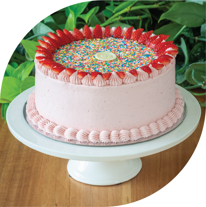 a pink strawberry kids cake with 100s & 1000s sprinkles and fresh strawberries on top