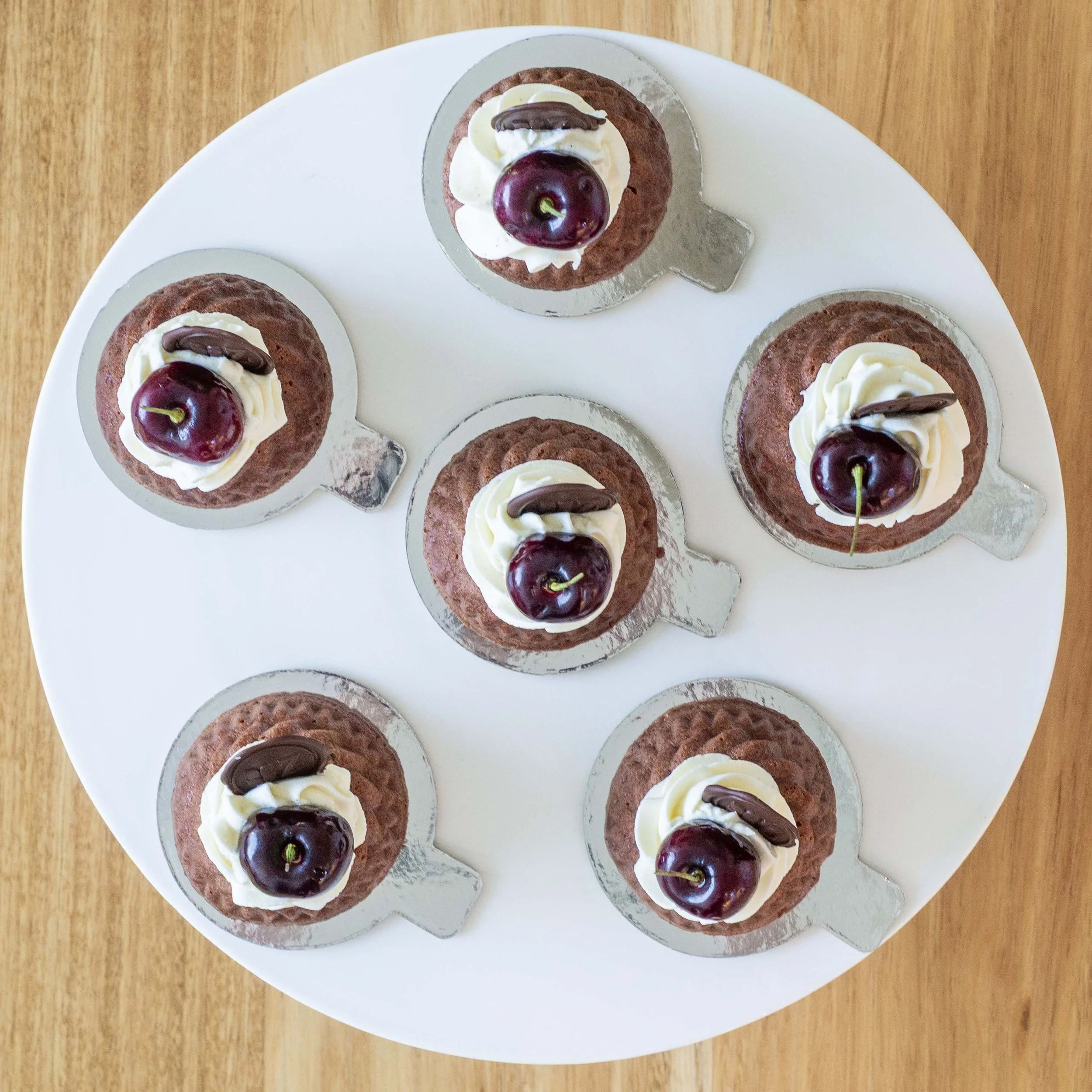 a view from above of six Schwarzwälder Kirschtorte or Black Forest petits gateaux with cherries on a cake stand