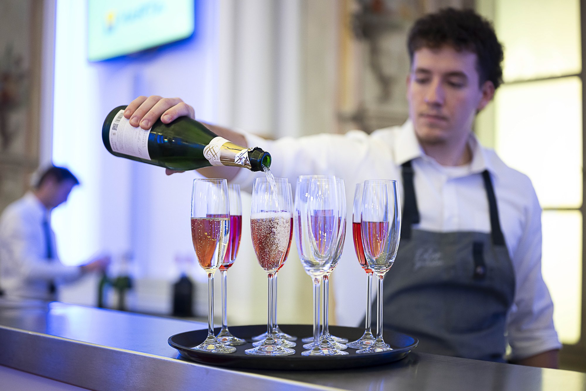 A waiter pouring champagne into glasses at a service station in a restaurant.