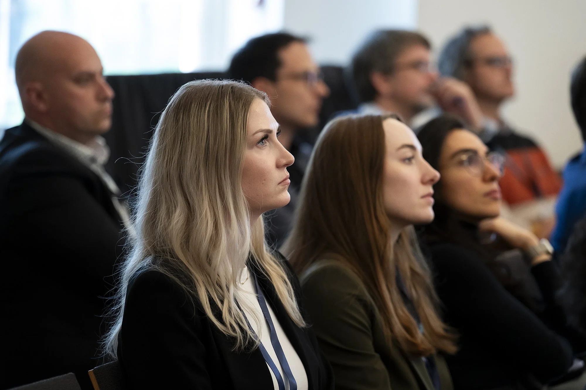 Group of people sitting attentively during a professional conference or meeting in a well-lit room.