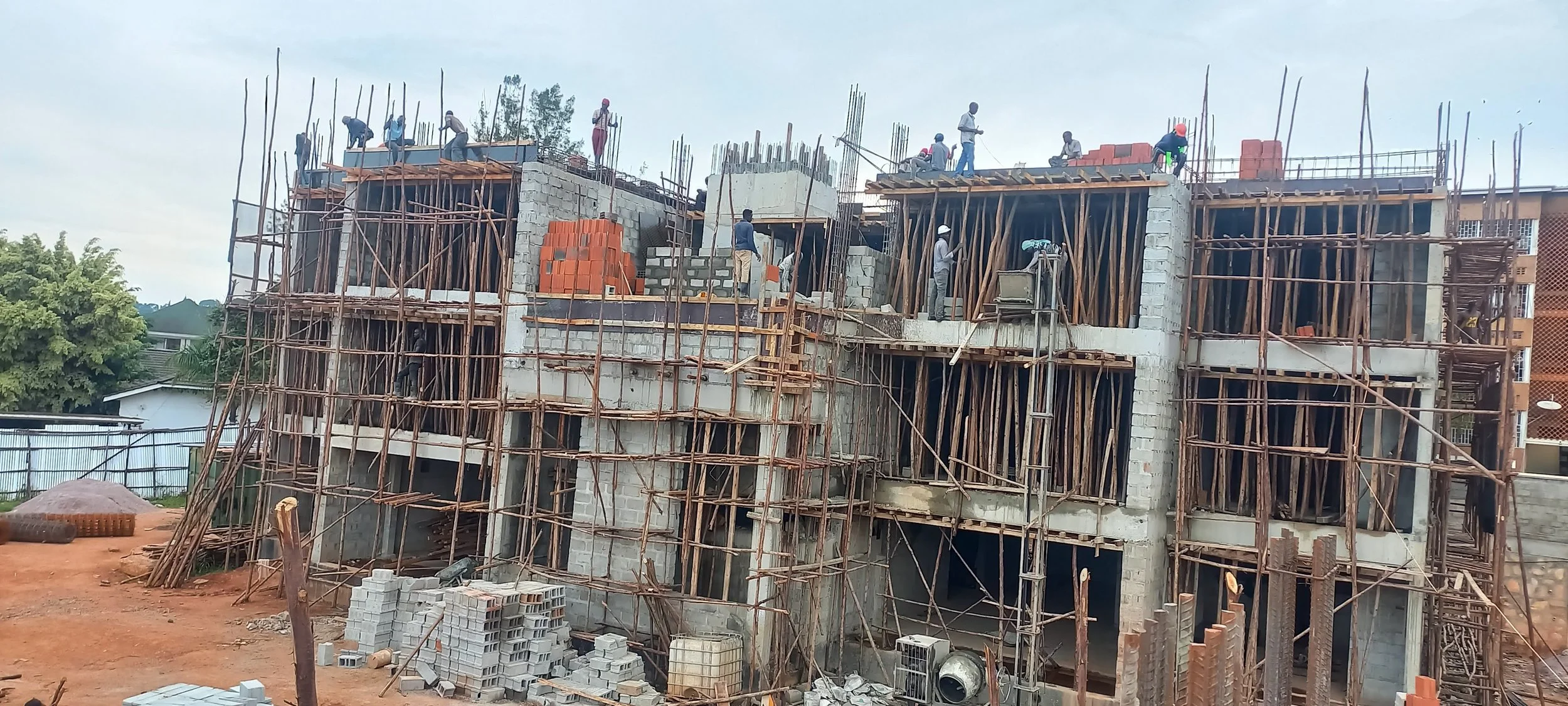Construction workers building a multi-story concrete structure with scaffolding and bricks.