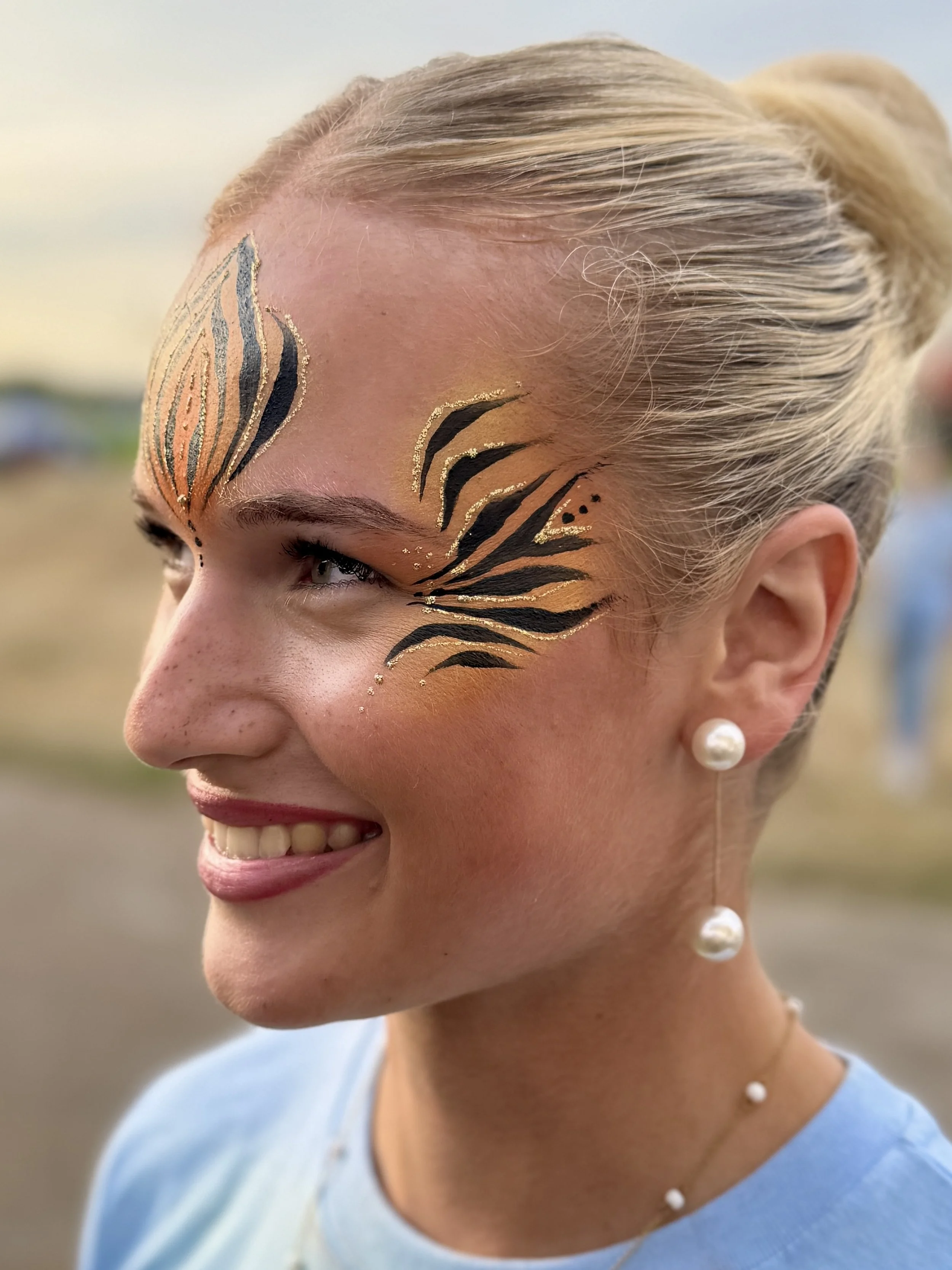 Young woman painted with gold and black tiger stripes
