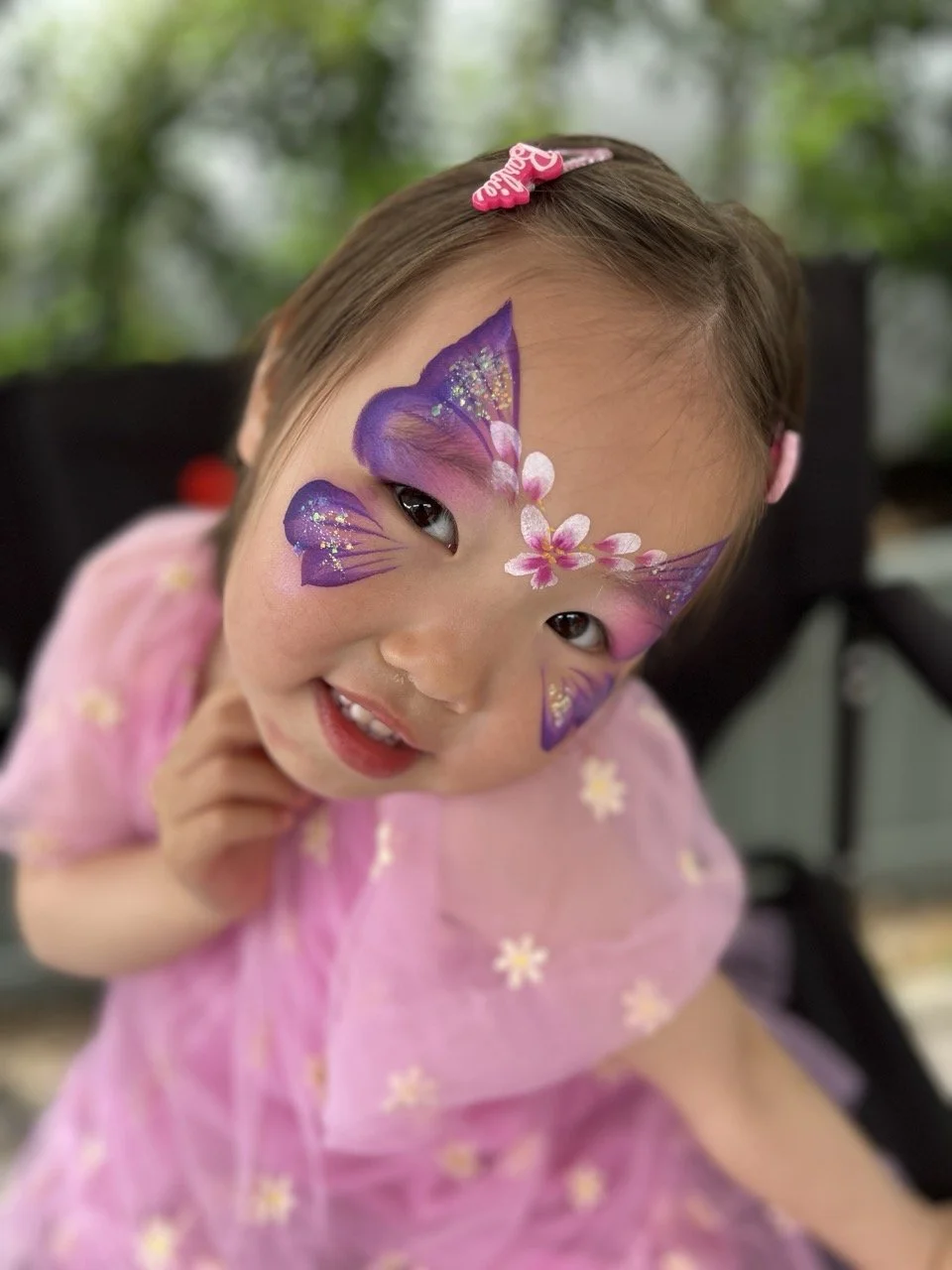 Girl in pink with a purple butterfly face paint