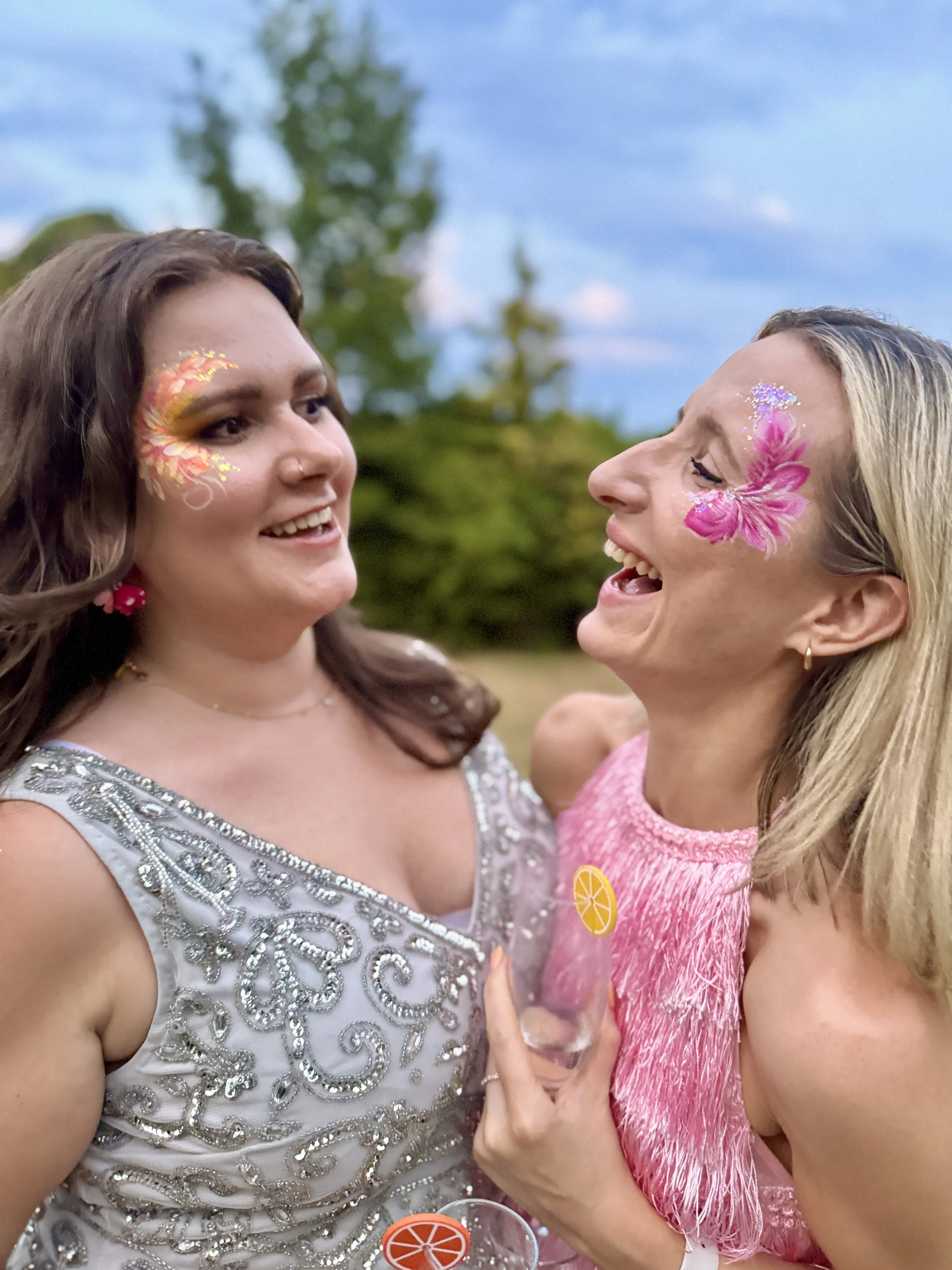 Two women with eye designs laughing together