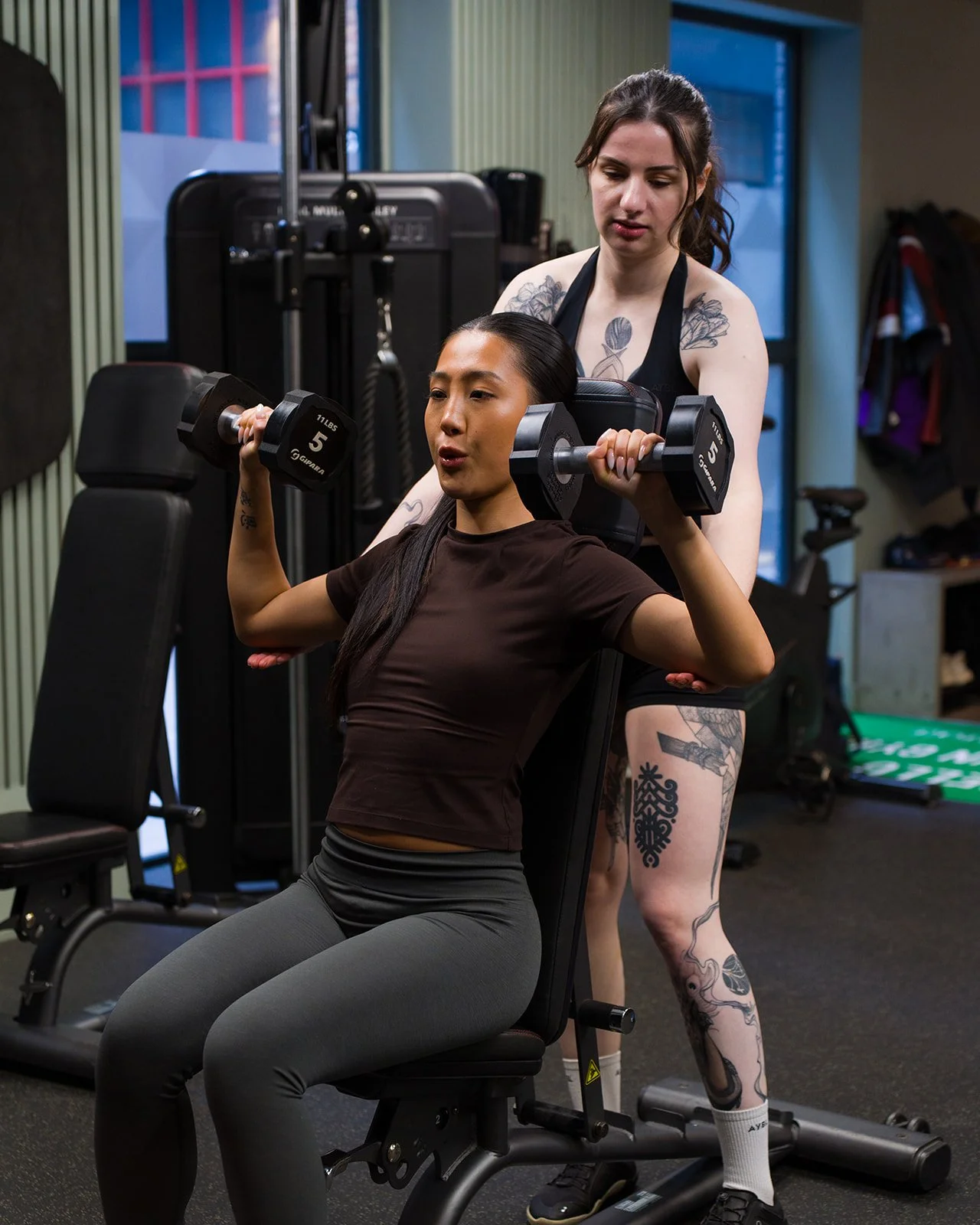 Personal Trainer coaching a client's correct depth on a dumbbell shoulder press exercise