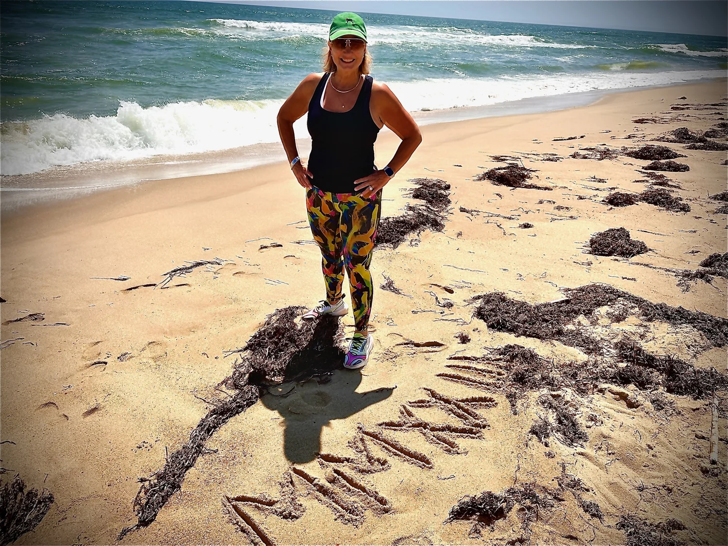 Marianne Moore smiling on a sunny beach beside the ocean