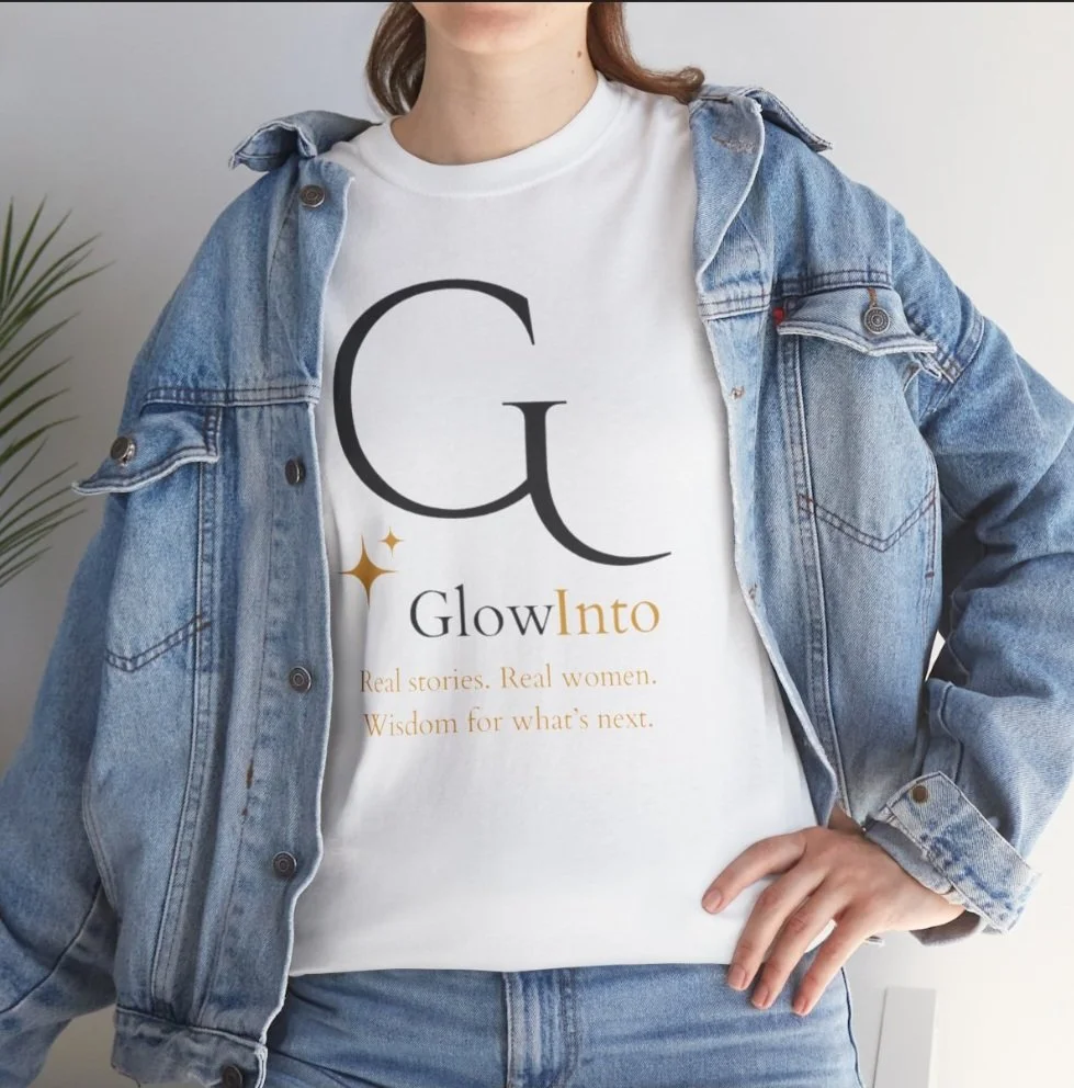 A woman wearing a white T-shirt with the logo 'G' and the words 'Glow Into' printed on it, layered with a denim jacket, and standing in front of a light background.