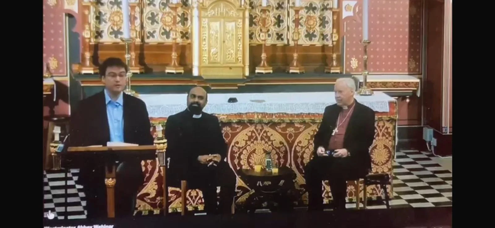 James Gordon Reid Haveloch‑Jones speaking at the Westminster Abbey webinar colloquium, with Allan Pallana and Bishop Christopher Lowson, the Westminster Abbey Commonwealth Theologian, seated behind him in a chapel setting.