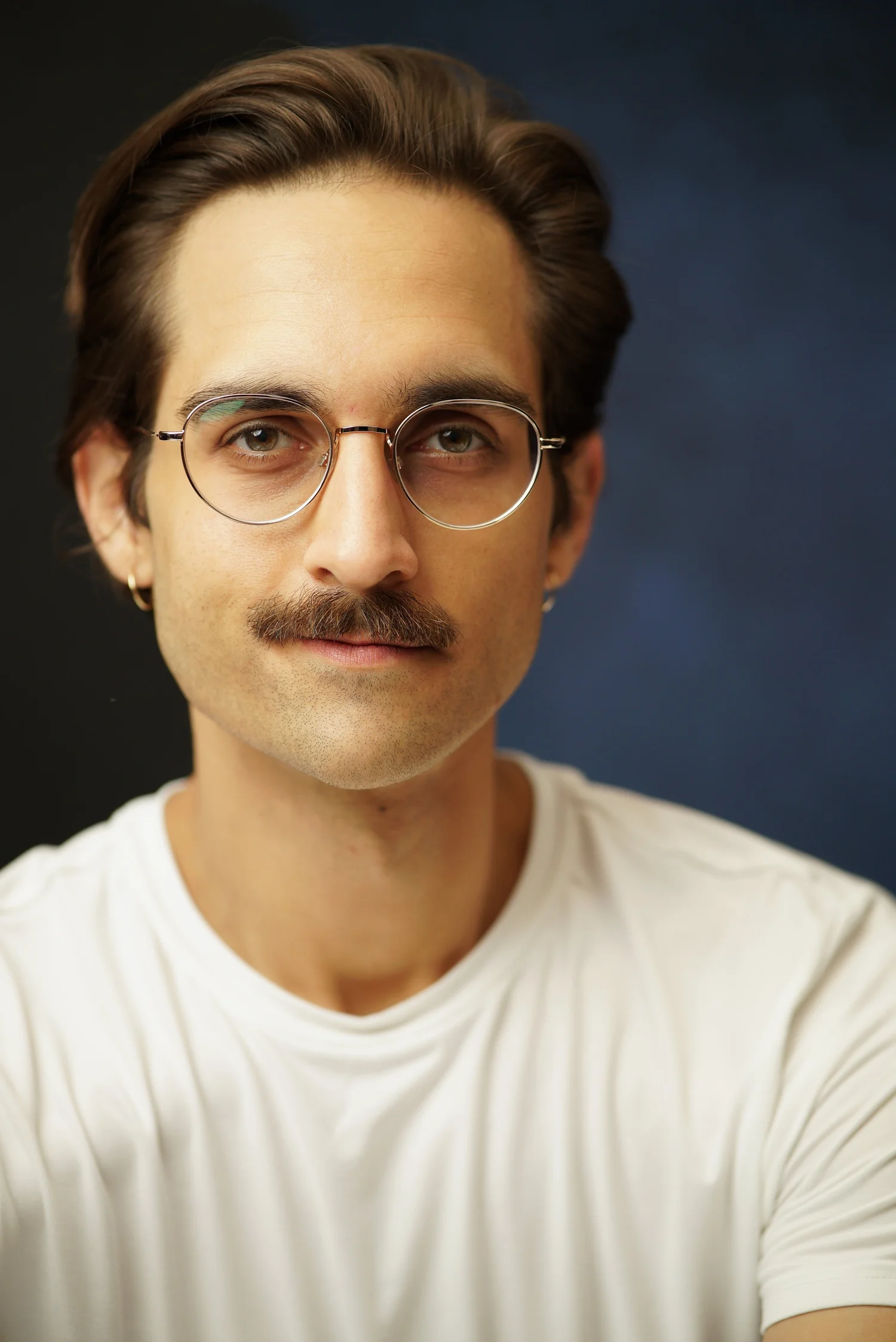Milan Babi universal headshot with glasses, white shirt, mustache, smirk
