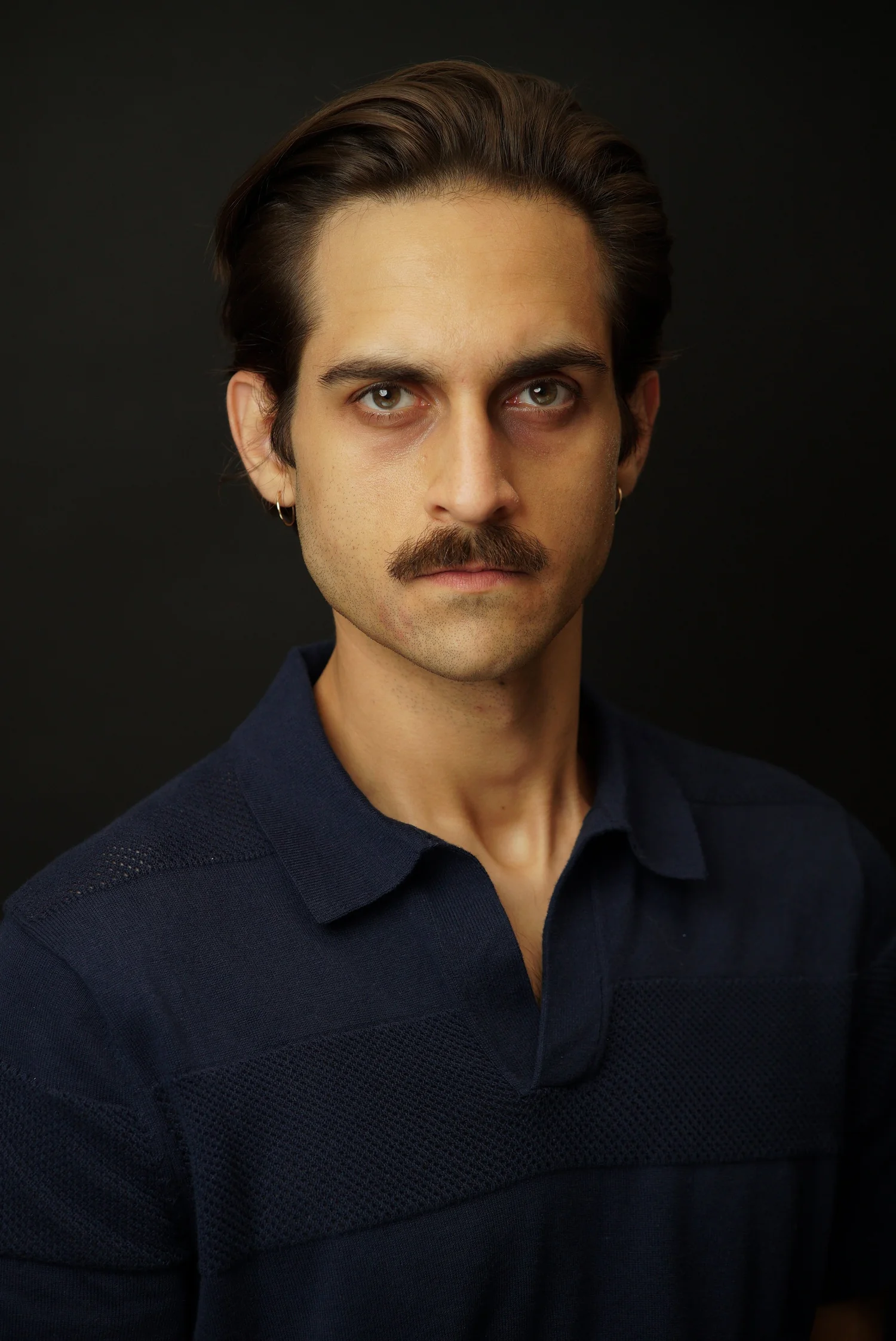 Milan Babi serious blue polo mustache headshot