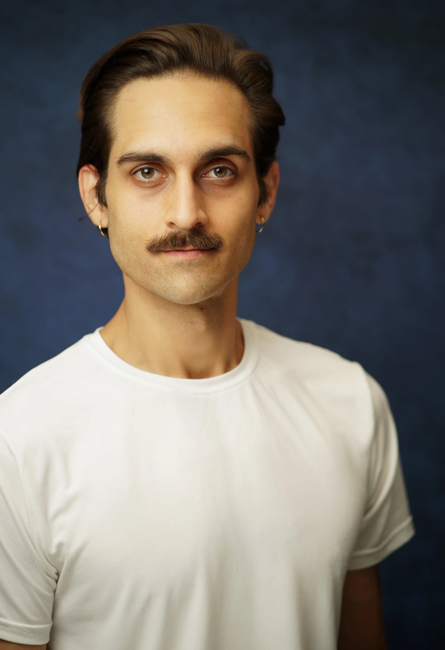 Milan Babi standing straight mustache headshot in white shirt