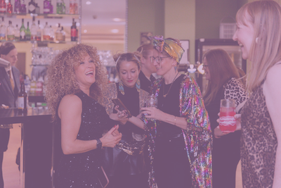 A group of friends laughing and enjoying an evening at a Common Ground event against the backdrop of a bar