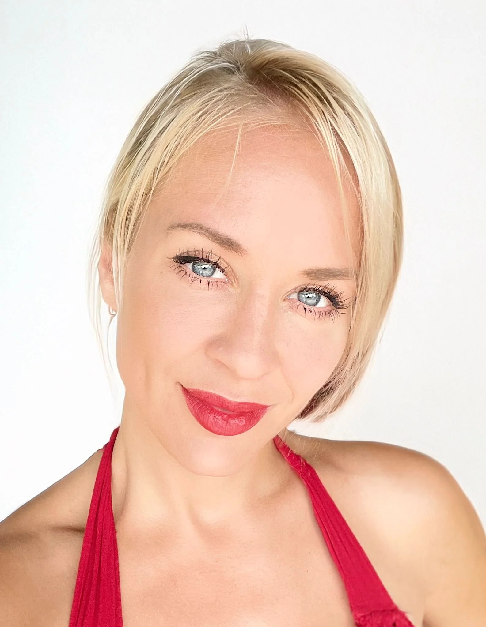Ragazza con capelli corti biondi, occhi azzurri, sorriso e vestito rosso