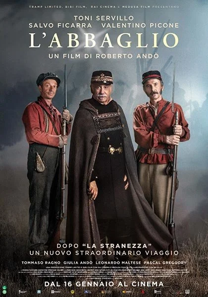 Locandina del film "L'abbaglio" con tre uomini in costumi tradizionali italiani, uno al centro con cappotto scuro e due ai lati con abbigliamento rosso, sfondo scuro e nebbioso.