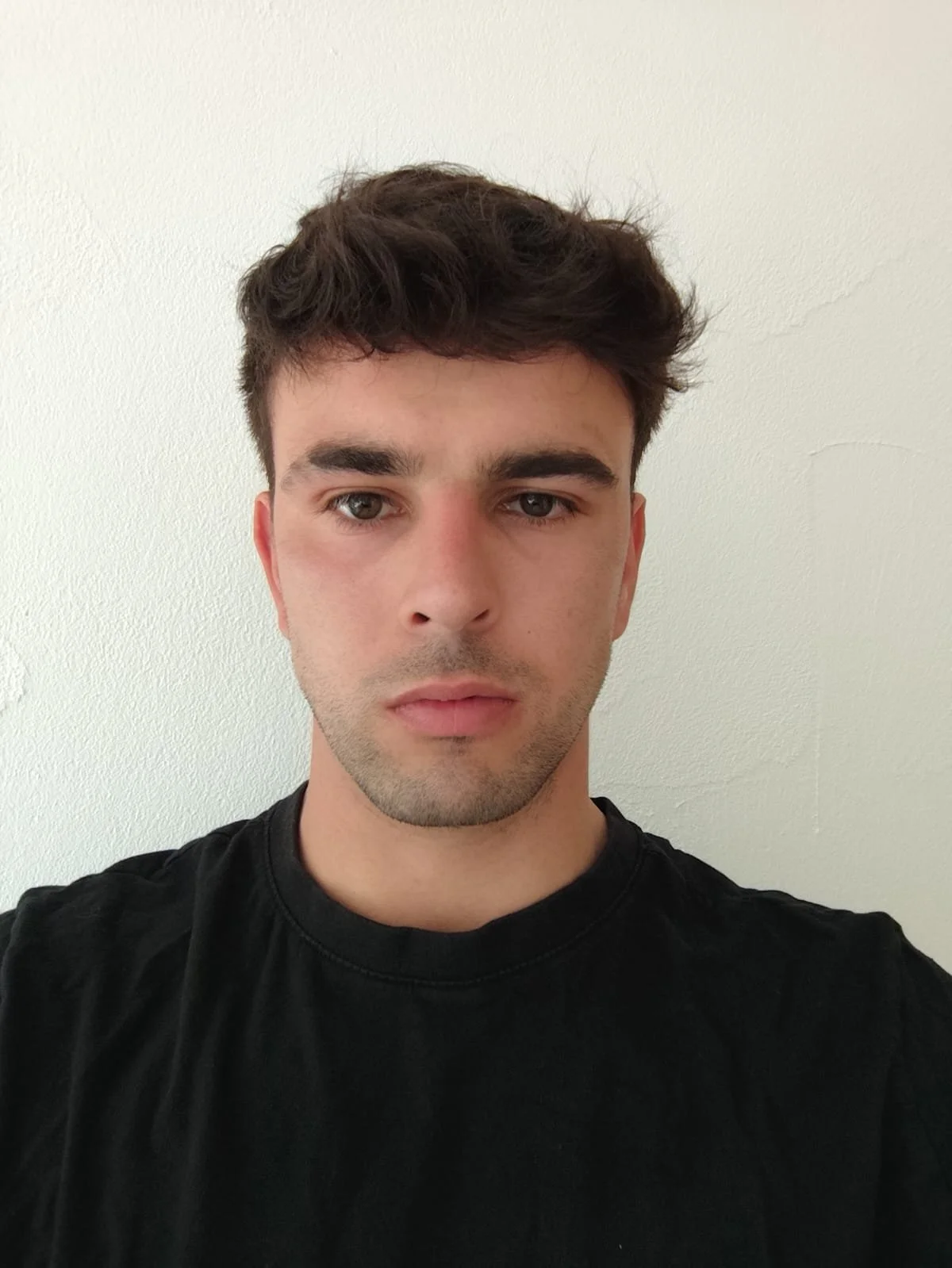 Ragazzo con capelli castani corti, occhi chiari, che indossa una maglietta nera, con sfondo bianco.