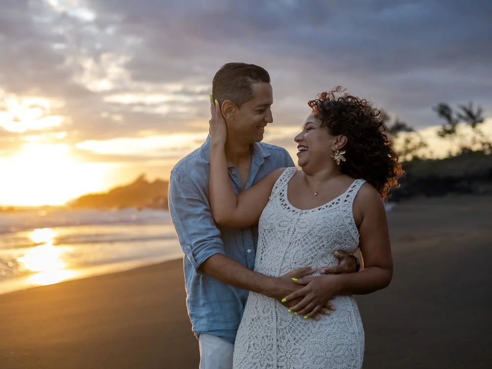Un couple heureux se regarde et s'aime sur la plage au coucher du soleil.