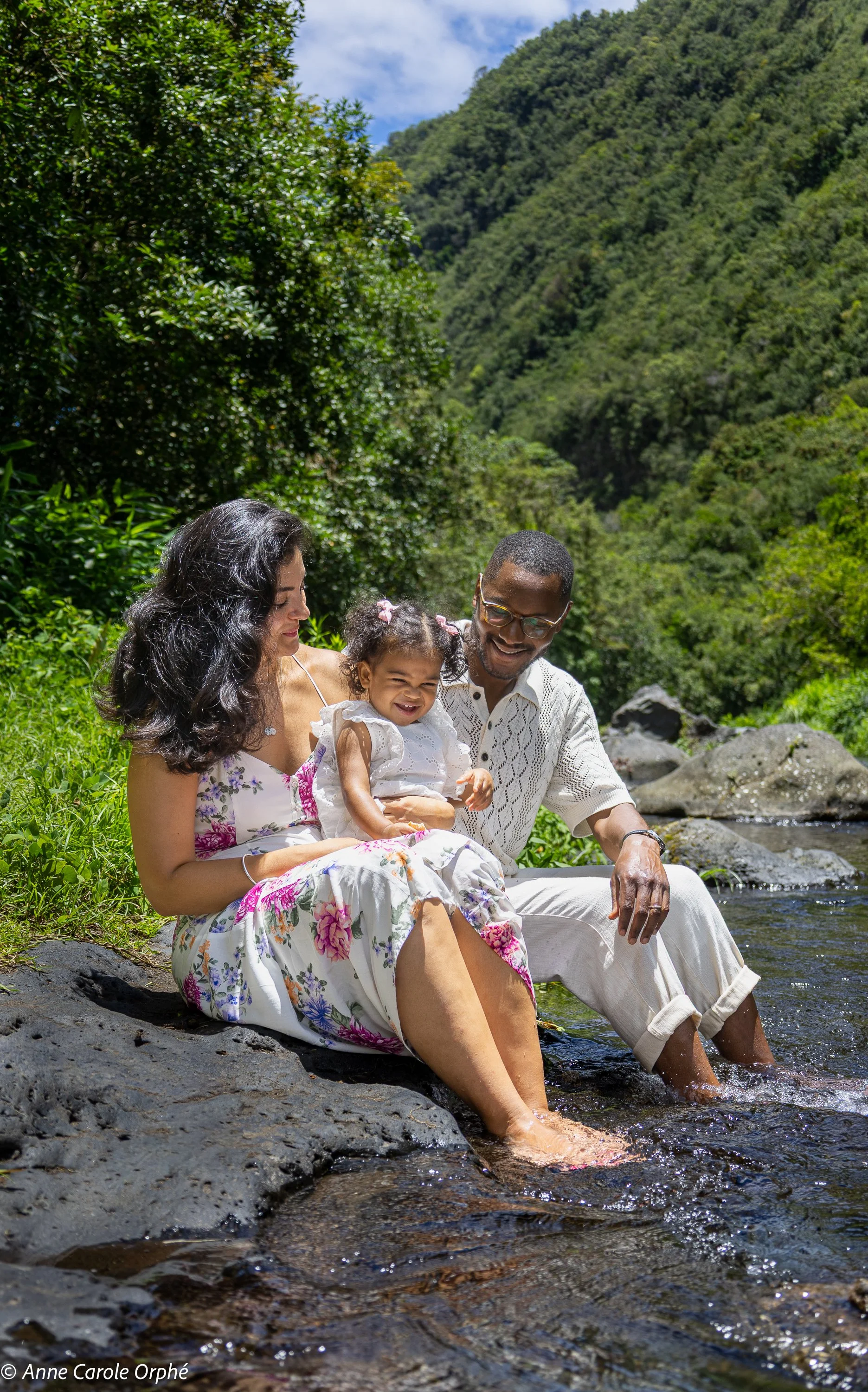 Une famille assise au bord d'une rivière entourée de végétation luxuriante, profitant d'un moment de détente en plein air.