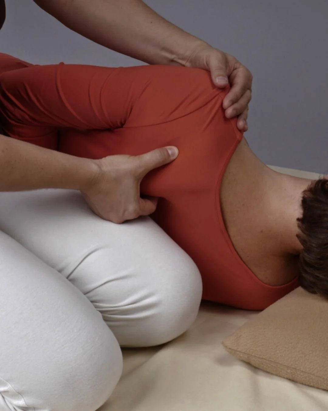 Eine Person erhält eine Shiatsu-Anwendung am Rücken, während sie auf der Seite liegt.