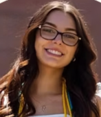 A young woman with glasses and long brown hair, smiling outdoors.