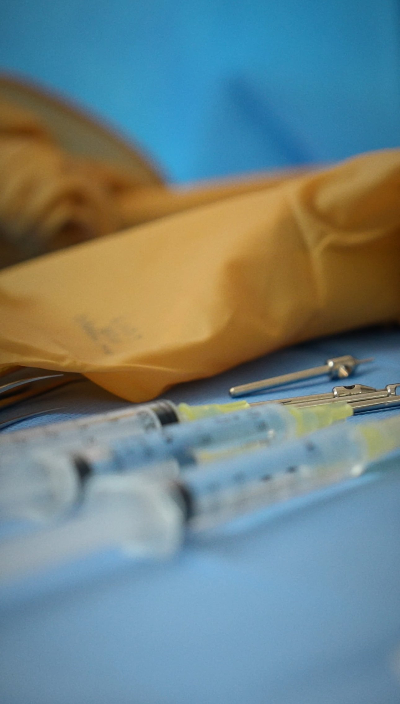 Objets médicaux sur une surface bleue, y compris des seringues, des outils chirurgicaux et un sac jaune