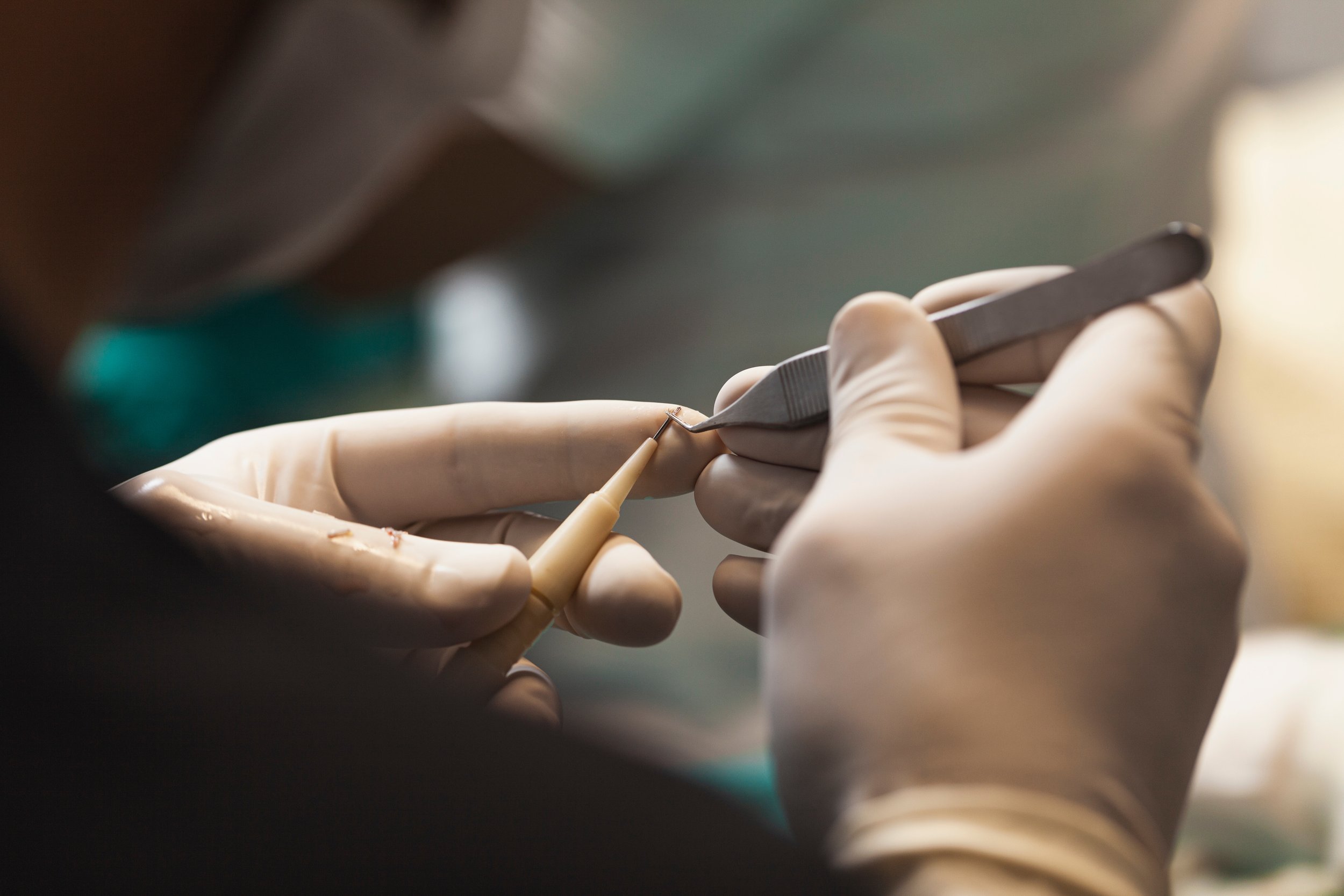 Un professionnel utilisant des outils de précision pour effectuer une intervention, portant des gants en latex.