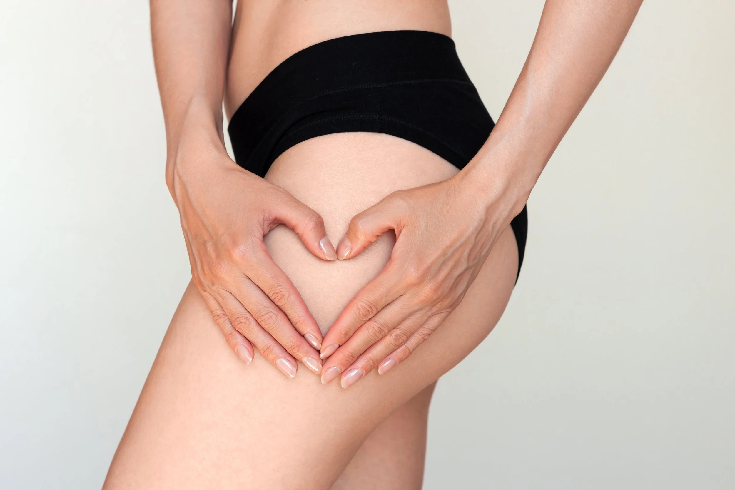 Une personne formant un cœur avec ses mains sur sa cuisse.