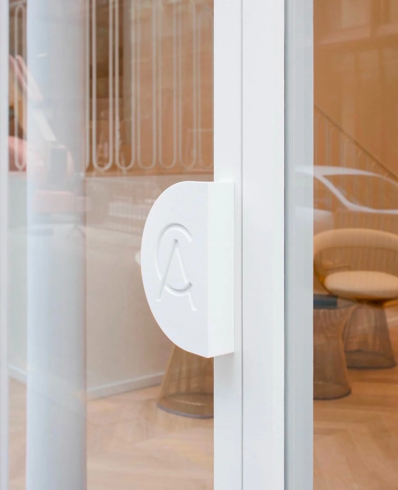 Une porte en verre avec une poignée blanche portant un symbole santé ou accessibilité.