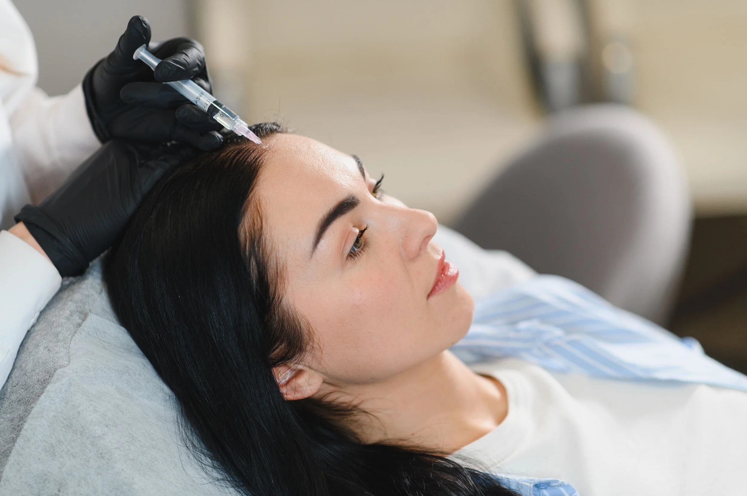 Une femme reçoit une injection ou une procédure esthétique au visage dans un contexte médical ou clinique.