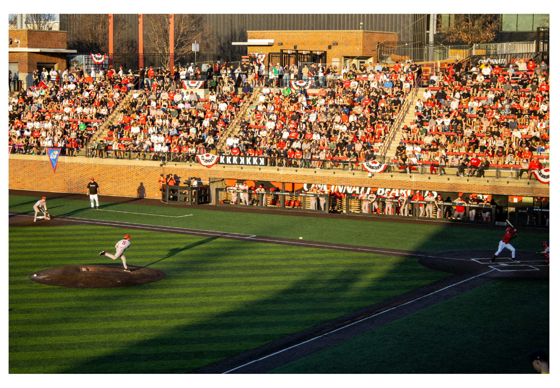 A baseball game in progress with players on the field and fans in the stands decorated for a patriotic celebration.