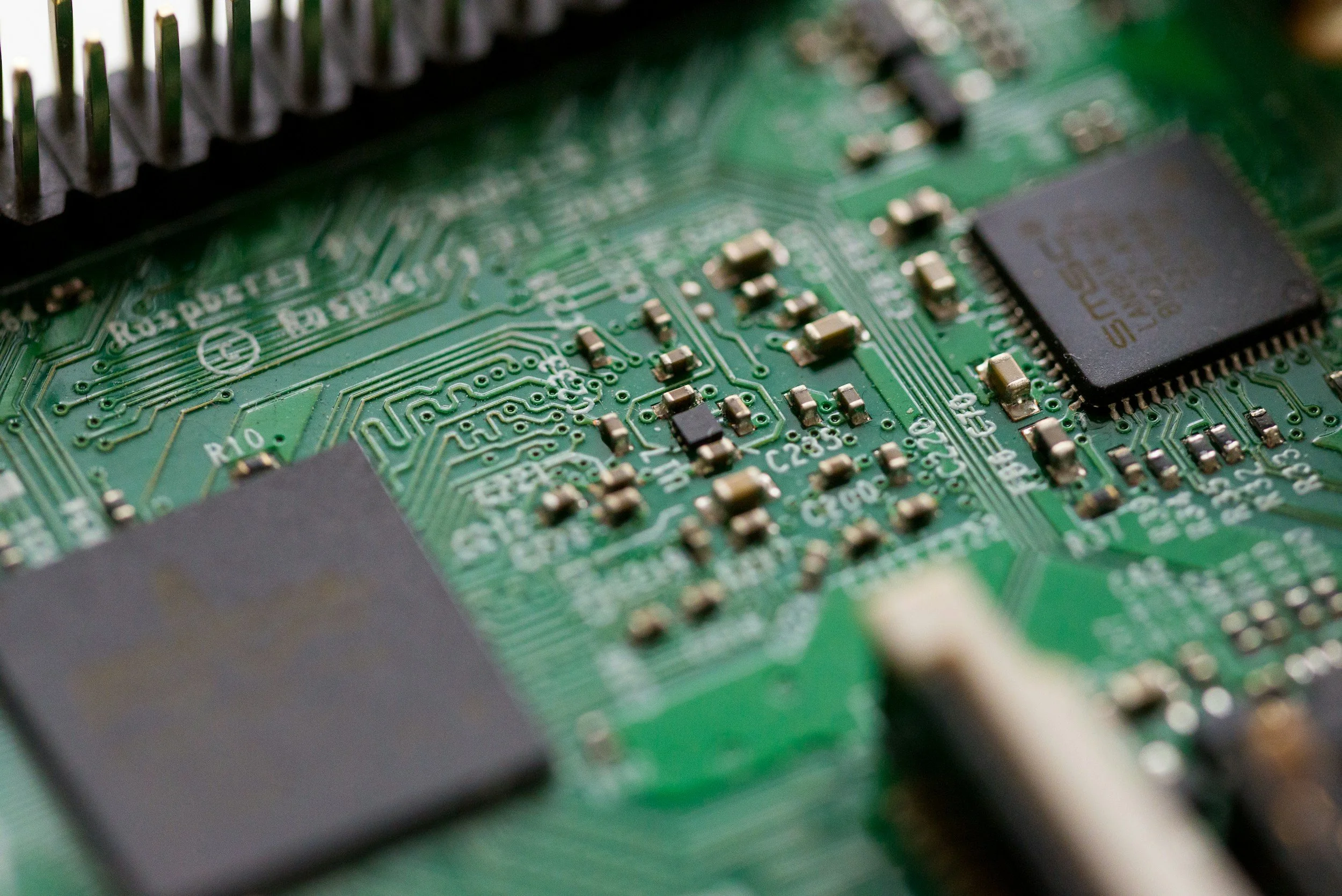 Close-up view of a green printed circuit board with various electronic components and integrated circuits.