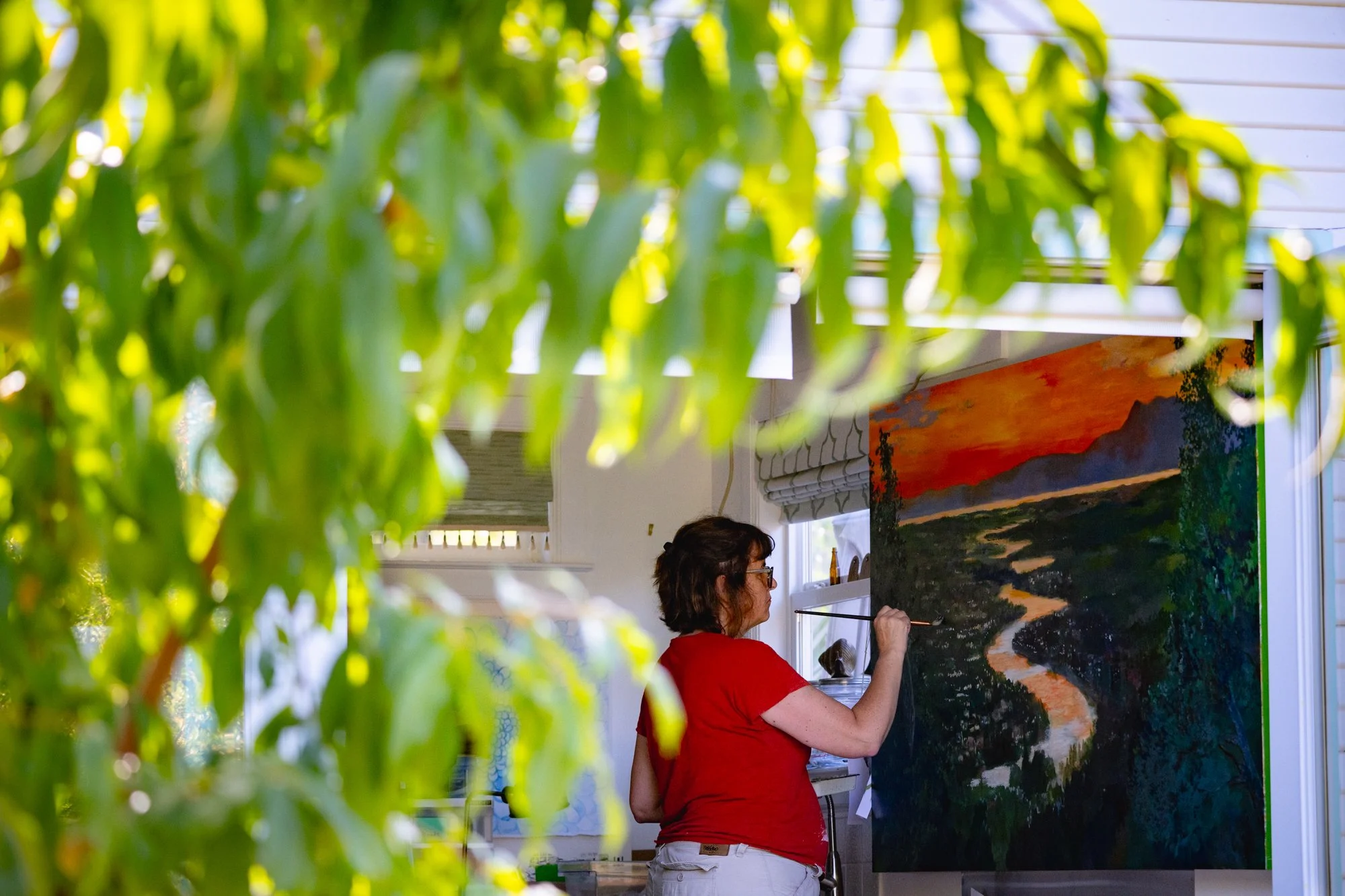 Kristina Young painting River of Light in her backyard studio with the doors open