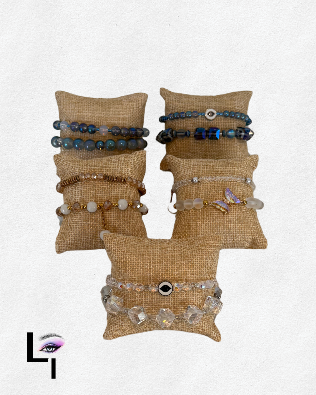Six bracelets displayed on small burlap pillows, one set of three on each pillow, with a stacked display on a beige background.