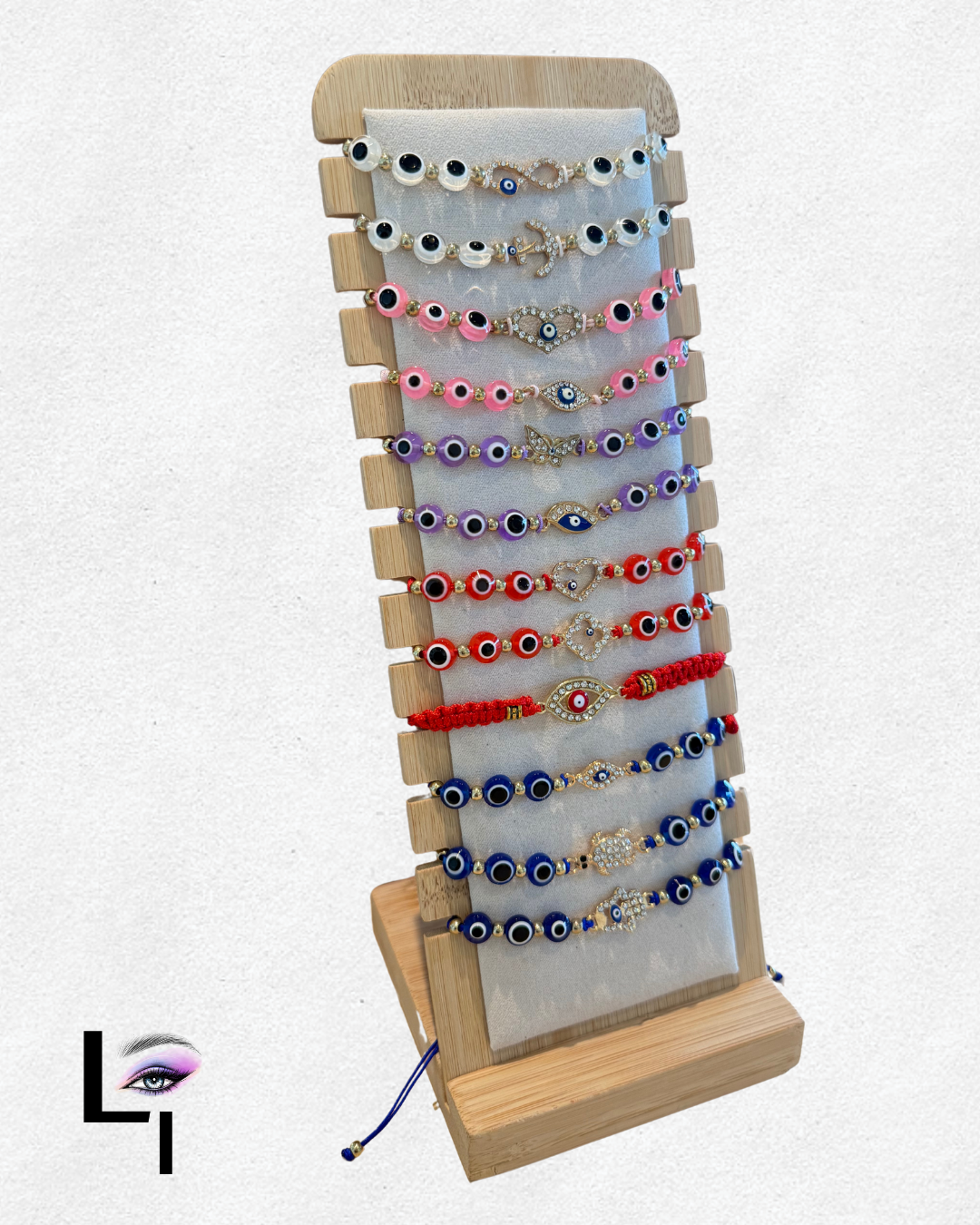 Display stand with multiple colorful evil eye bracelets, arranged in layers on a beige fabric background, under neutral lighting.